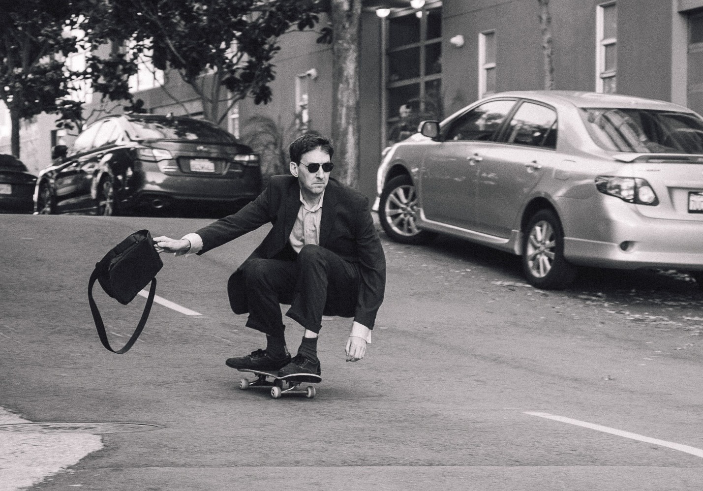 Chris skateboarding in a suit while holding a briefcase