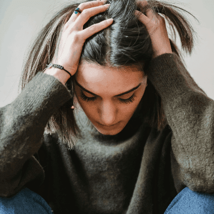 Close-up of a woman holding her head, symbolising anxiety and the supportive counselling offered by HeadHealth.