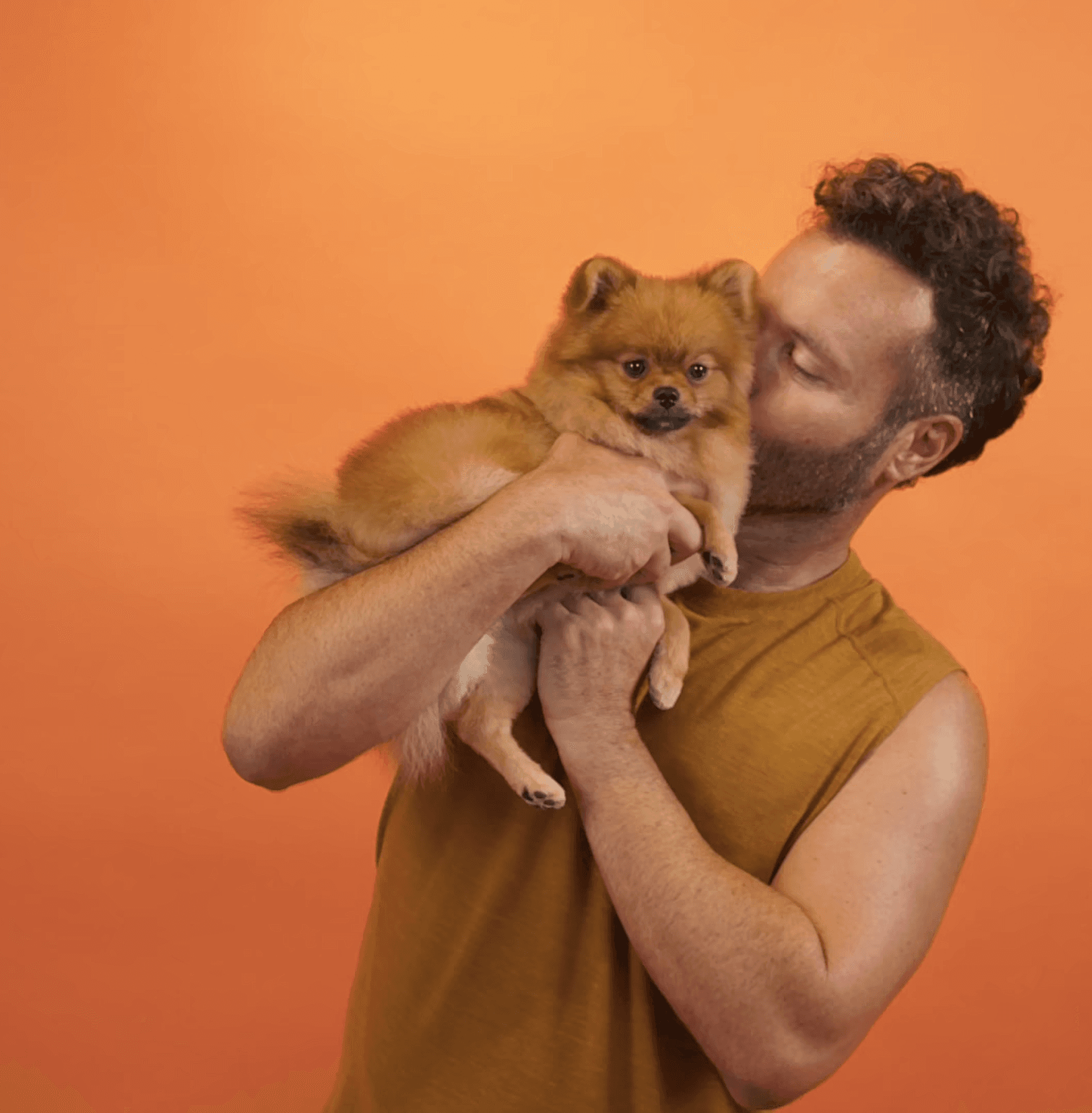 Joyful image of a man kissing his small fluffy dog to show love, trust, and personalized care.