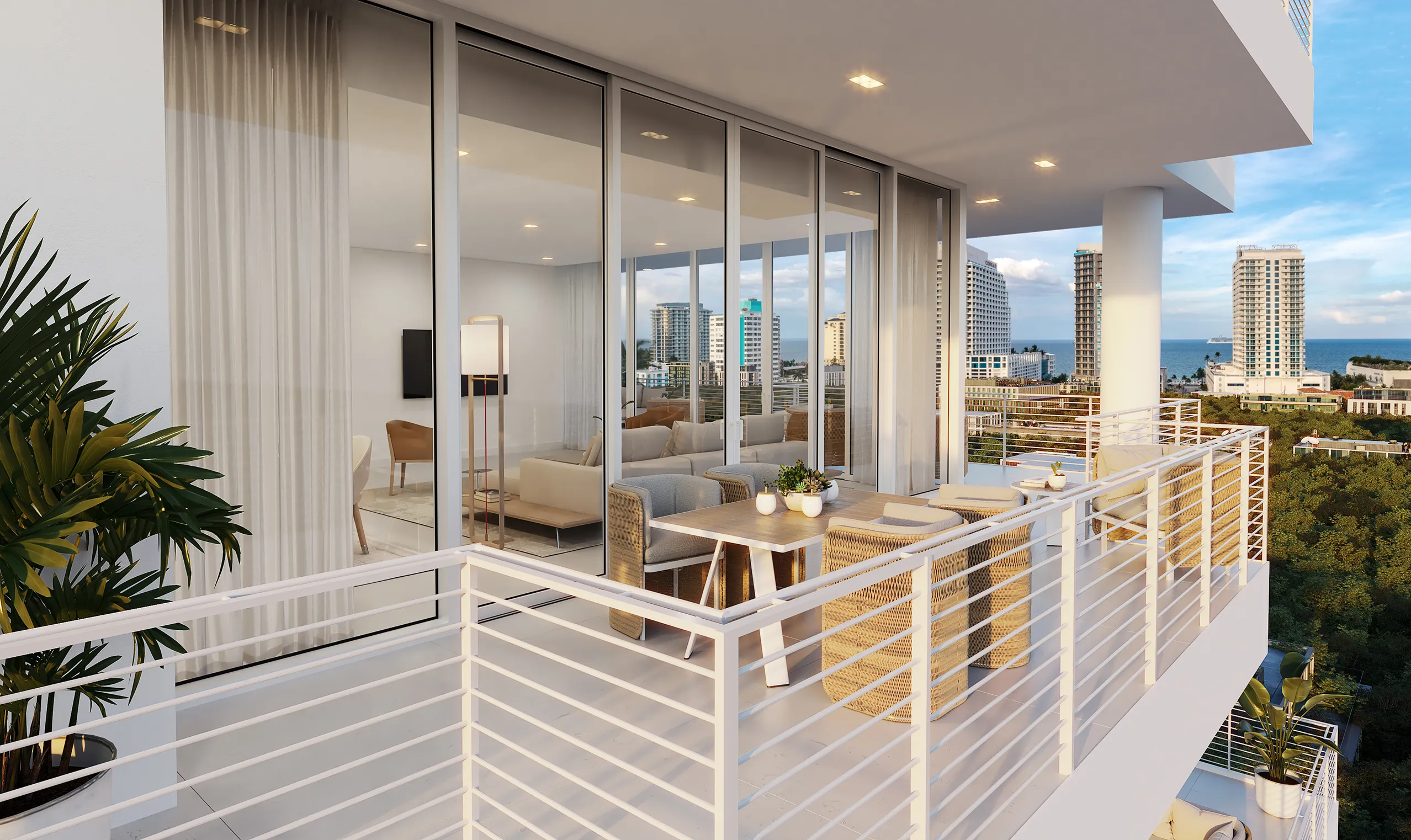 Modern apartment balcony with outdoor dining area, glass doors leading to a living room, city buildings, and greenery visible in the background.
