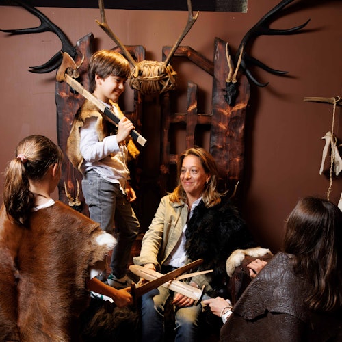 一群穿著中世紀服裝的人,其中一個人坐在木製的寶座上,四周環繞著鹿角,手裡拿著木劍。