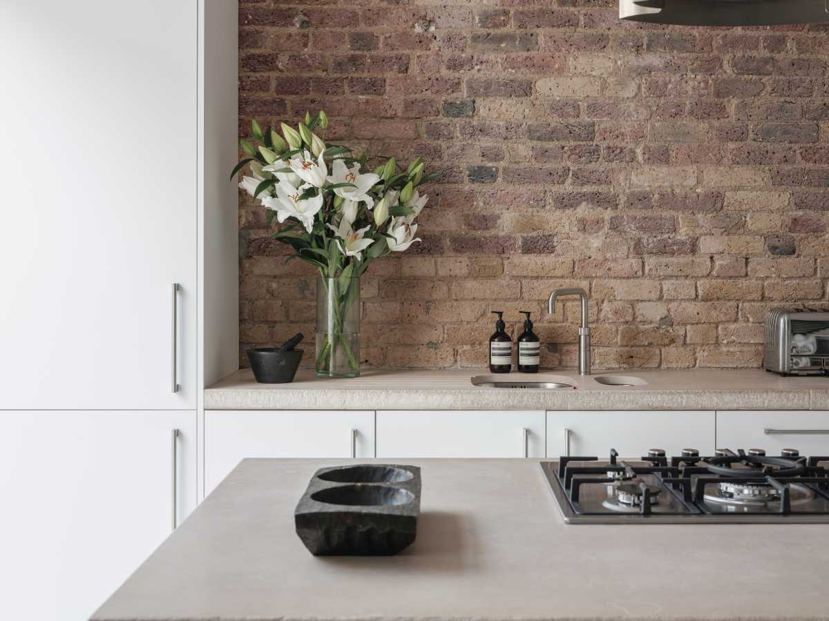 An overhead view of a bespoke bathroom vanity in a luxury London residential home, showing a custom-integrated sink carved from heavily veined natural marble stone with premium dark fixtures.