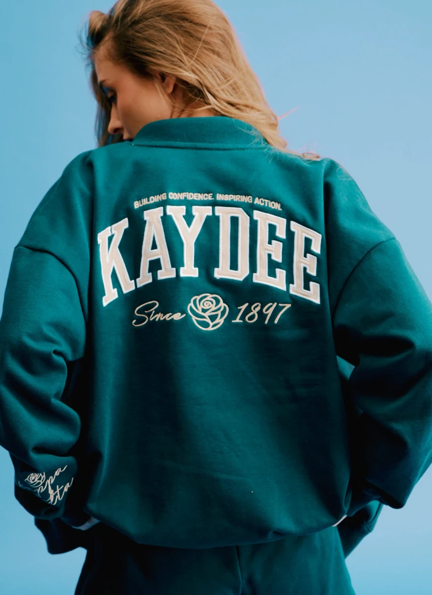 Back of a forest-green Kaydee sweatshirt with large varsity lettering and a rose graphic.
