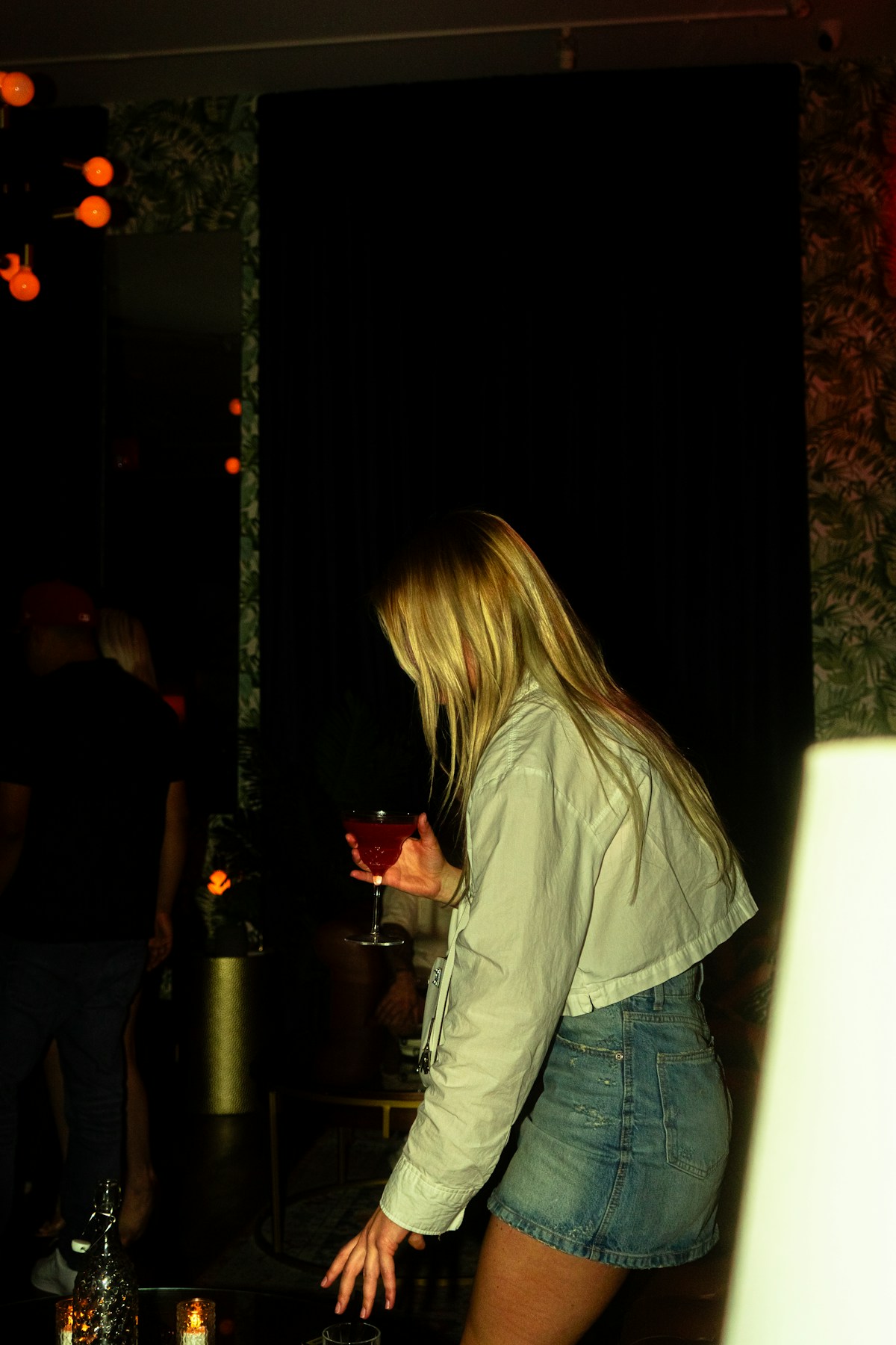 Guest holding a cocktail in a warm late-night bar