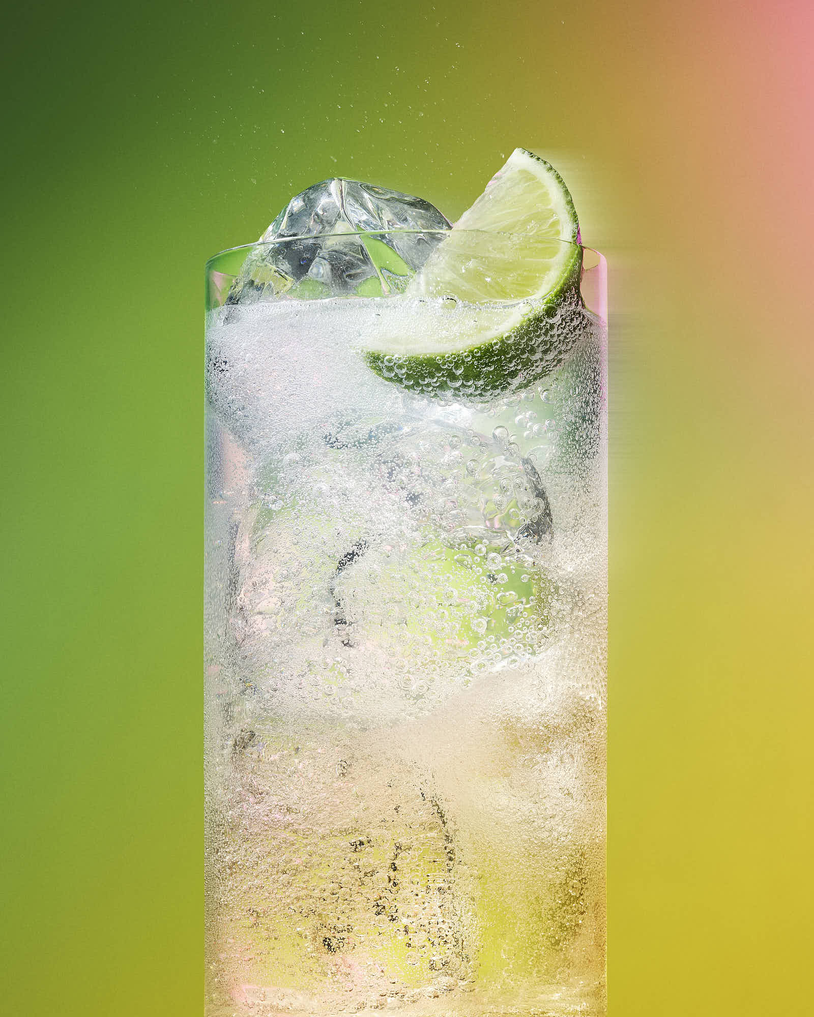 A refreshing cocktail with ice and a lime wedge, set against a vibrant gradient background.