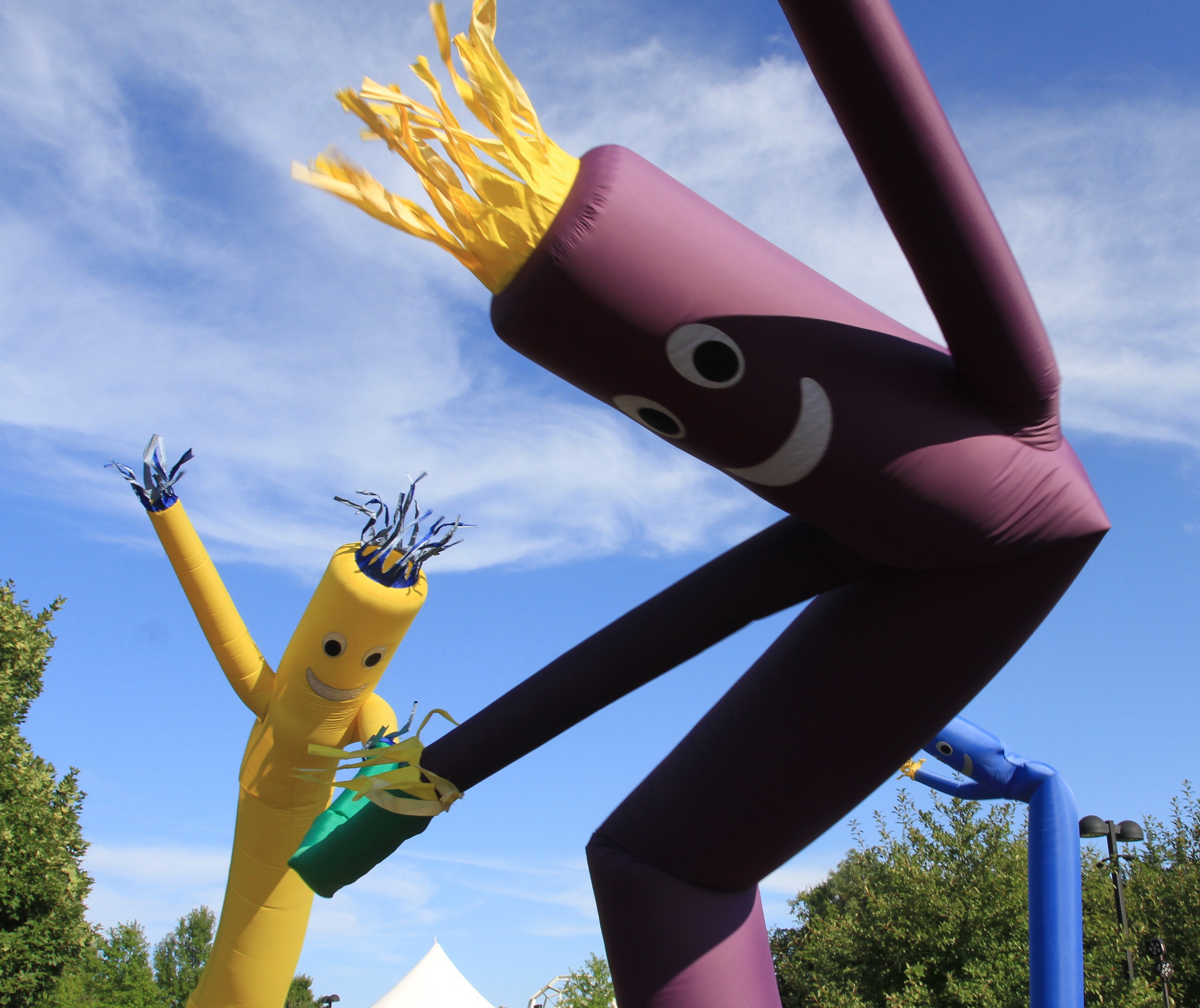 Colorful inflatable tube men dance in the wind against a clear blue sky.