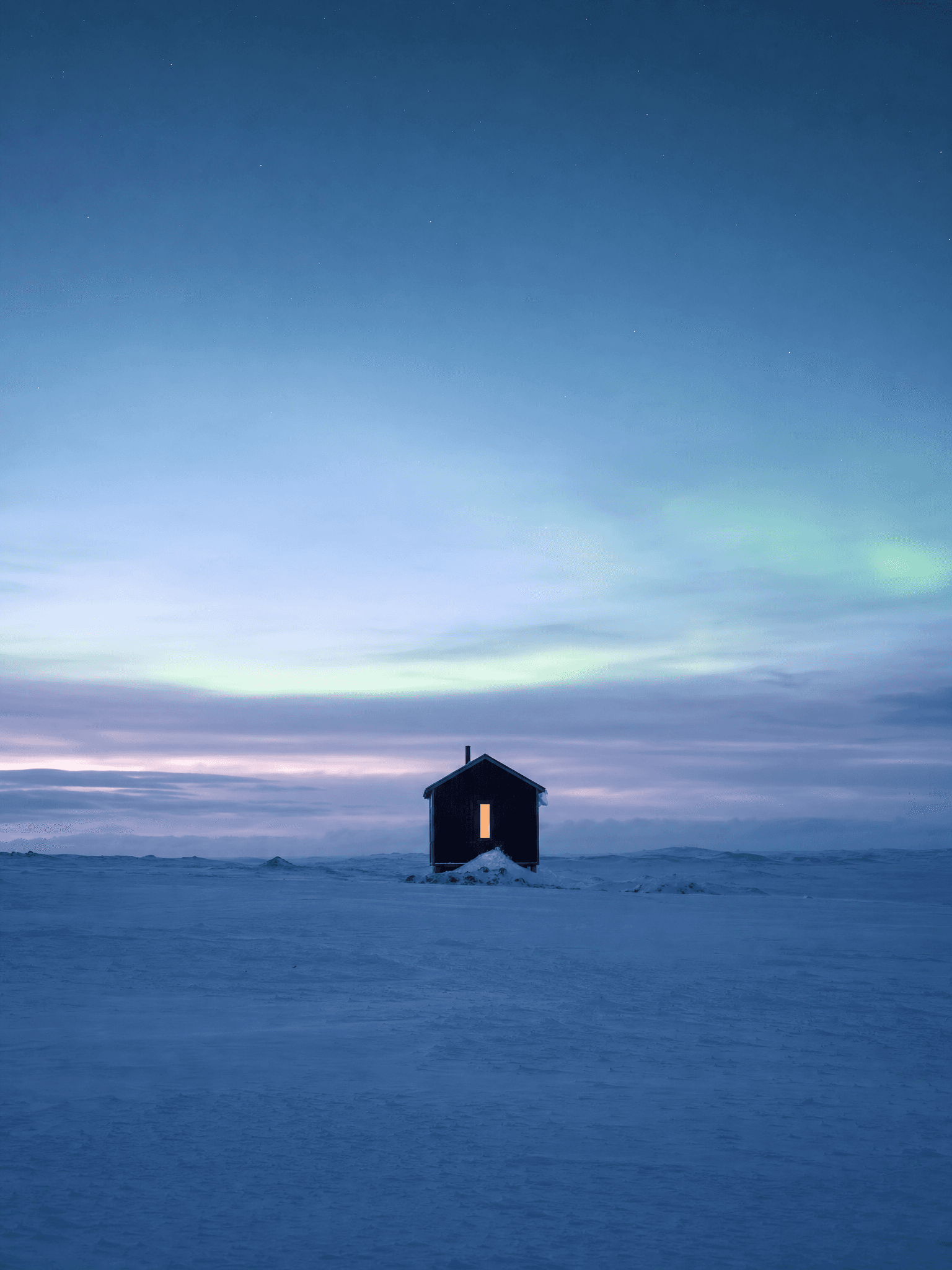 Small cabin on a snowy plain under a twilight sky