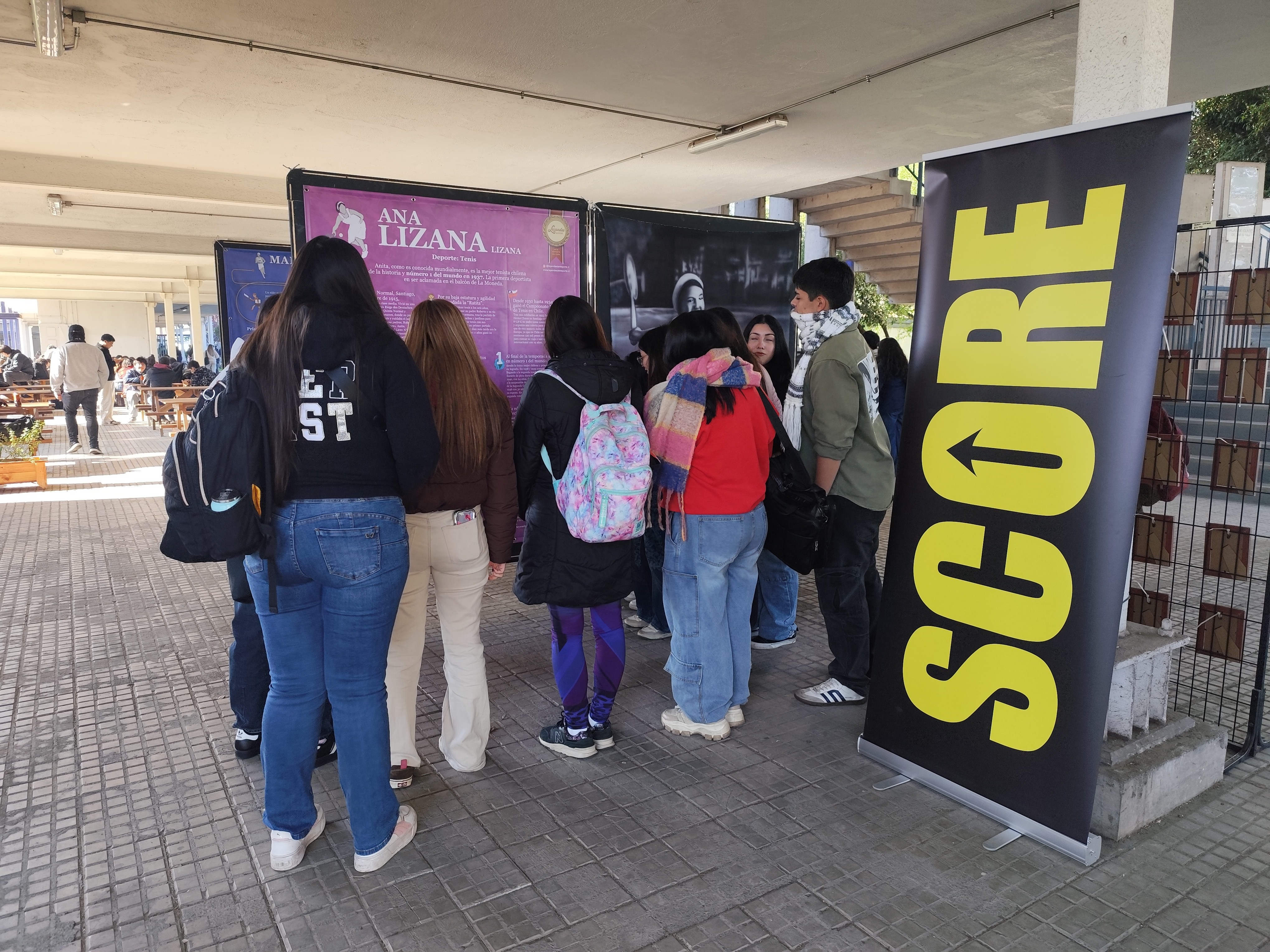 Asistentes observando la pintura de Ana Lizana, atleta chilena, en la exposición Leyendas del Deporte en USACH.