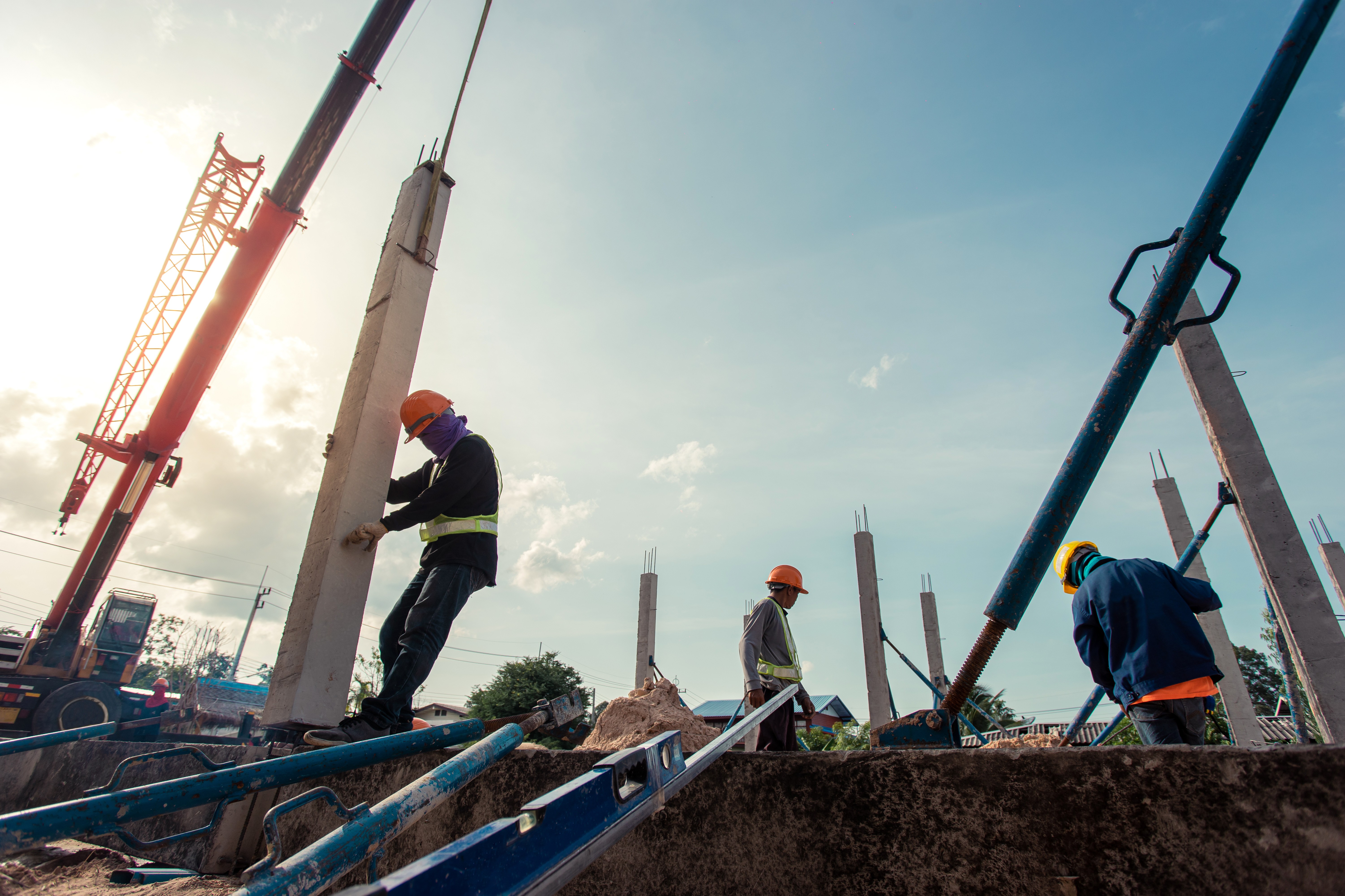 Workers erecting precast concrete columns with a crane at a construction site