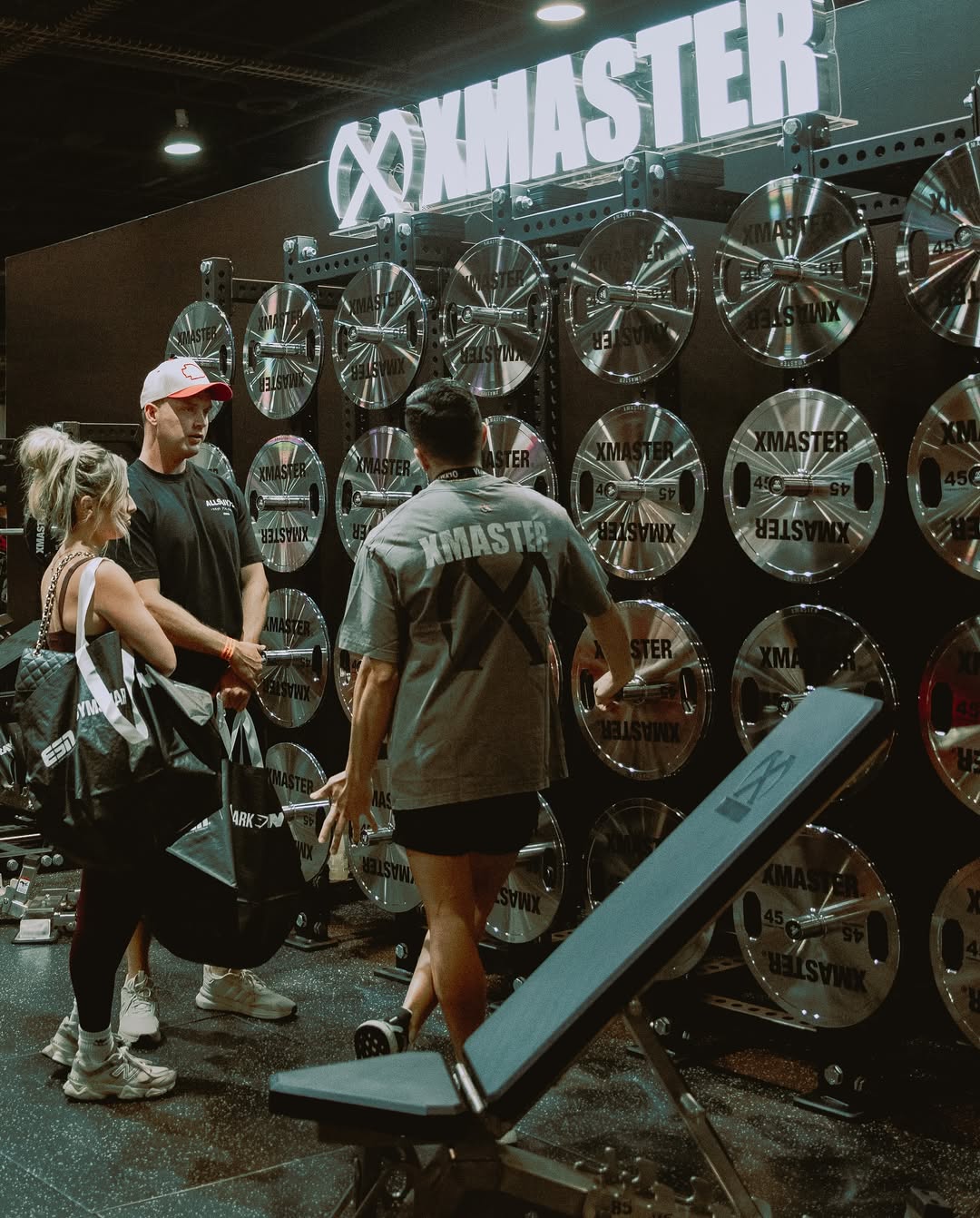 Two individuals are working out in a gym, focusing on dumbbells and strength training equipment.