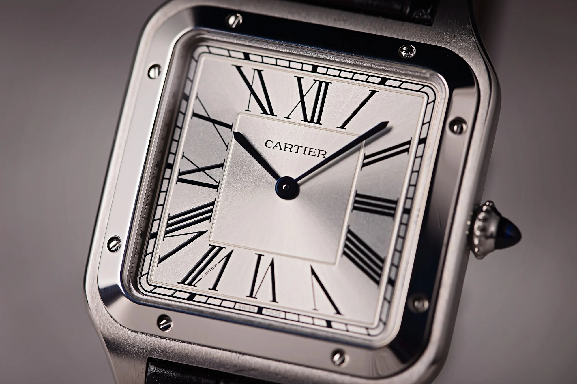 Cartier Santos watch close-up. Silver dial with roman numerals and black leather strap.