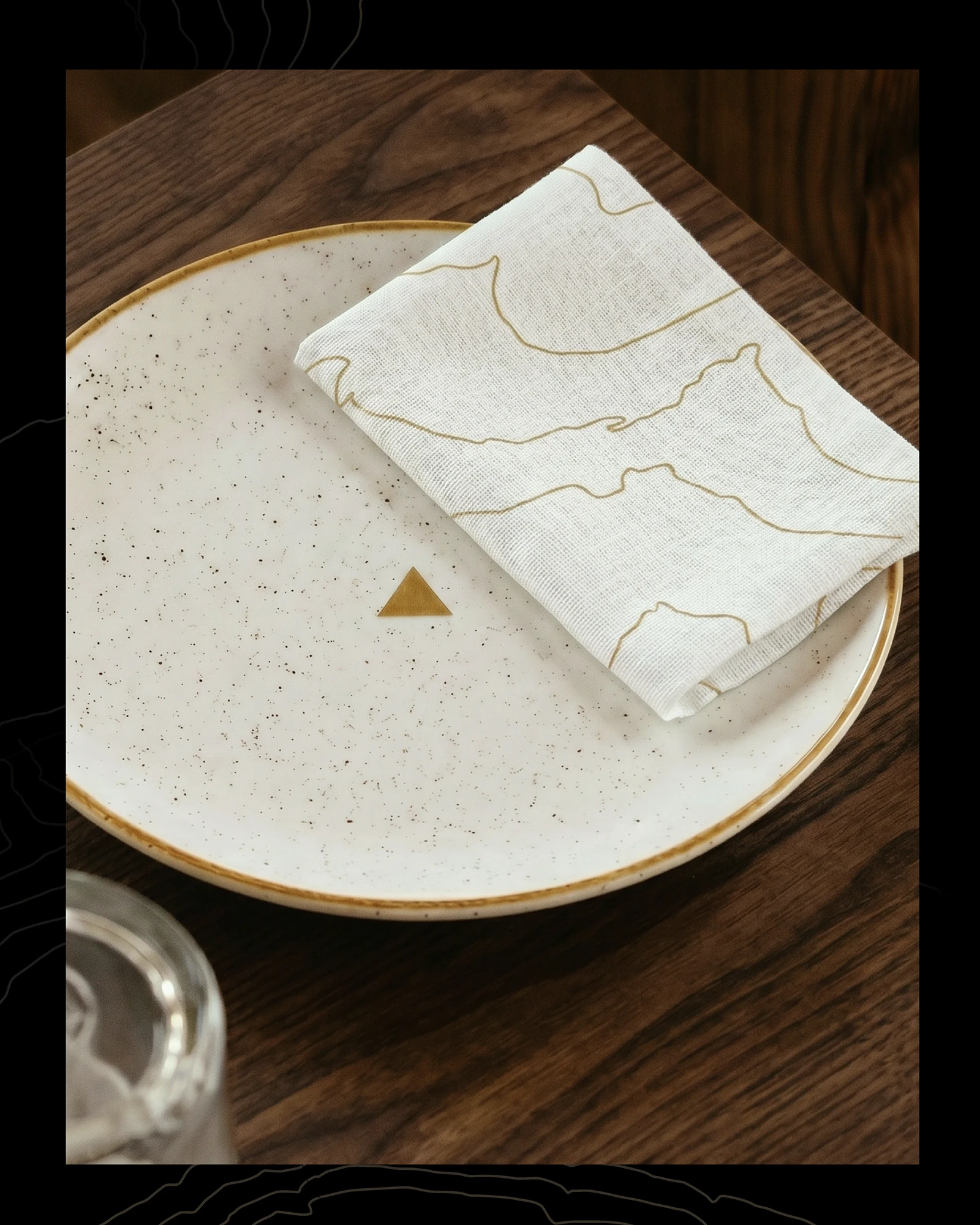Napkin with a topographic line pattern folded on a ceramic plate, brand identity design by Sebastian Saavedra