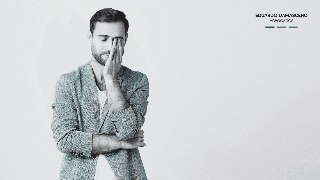 A couple sits on a park bench facing a serene pond, with two parked bicycles nearby, surrounded by lush greenery and a backdrop of tall apartment buildings under a clear sky.