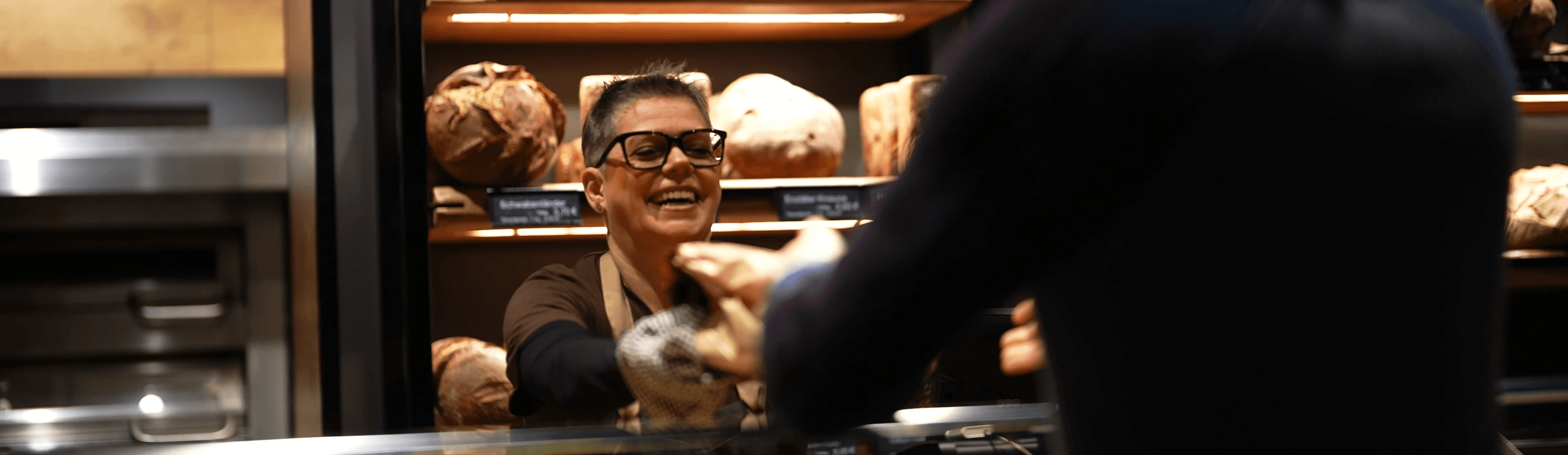 Mitarbeiterin lächelt hinter der Brot-Theke bei Bäckerei-Stöckle