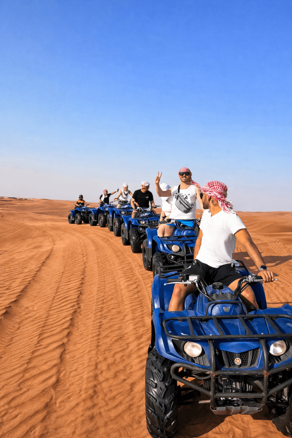 Group of tourists riding Yamaha 350cc ATVs during a Dubai desert safari rental experience with Dune Quest Tours