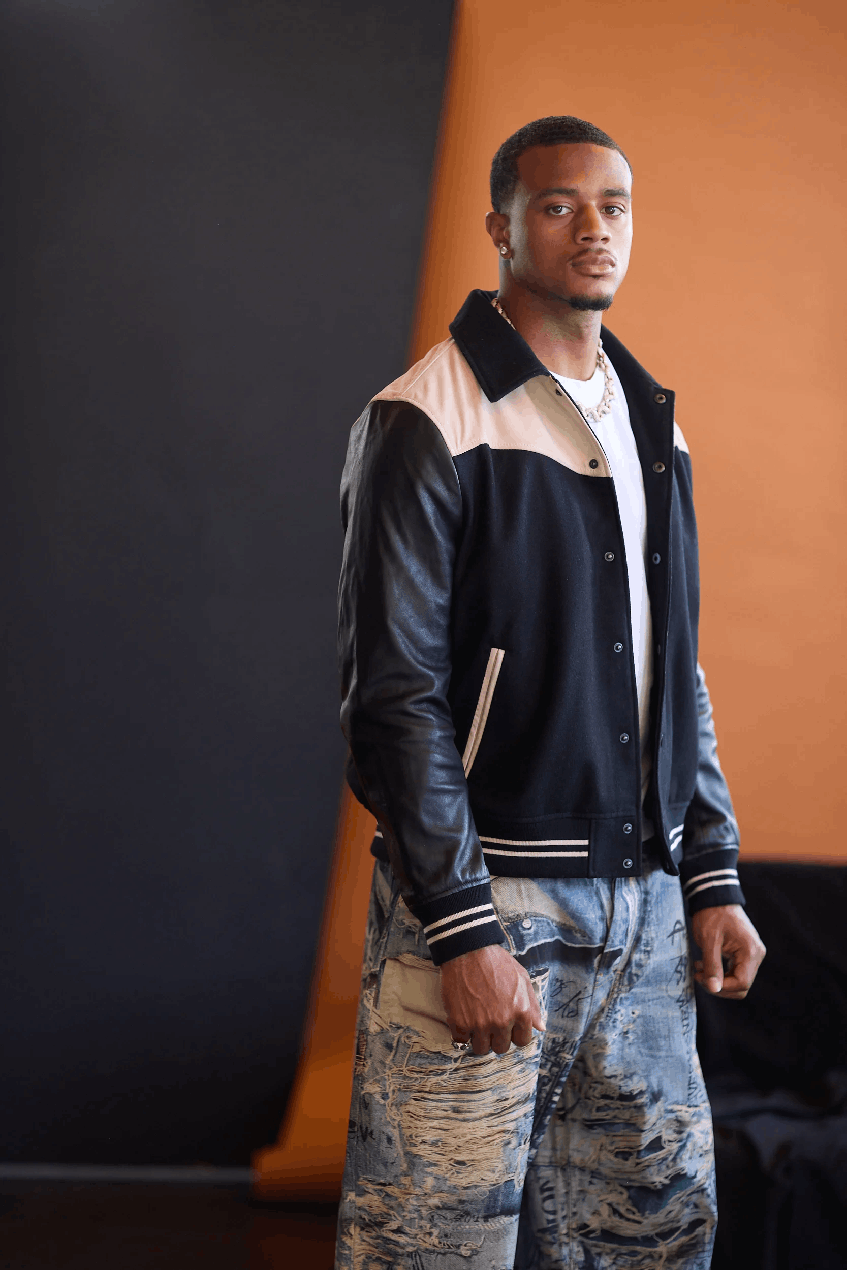 pat surtain poses in a leather jacket in front of an orange and blue background