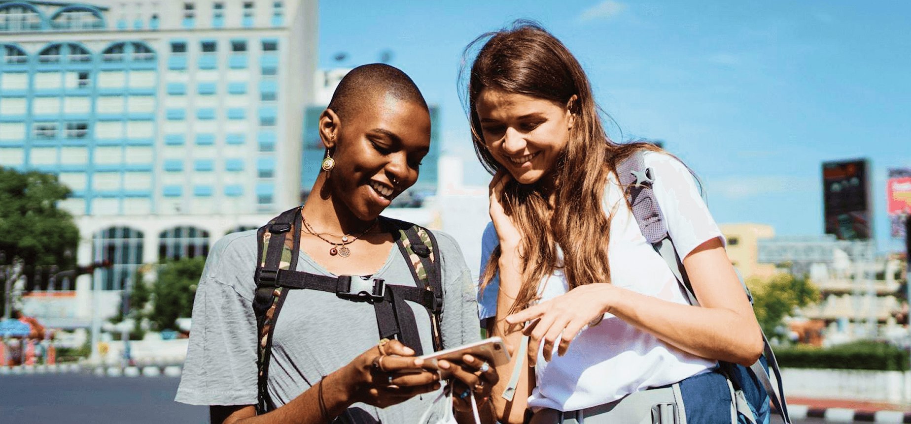 Two travelers checking their trip plan on a phone while exploring a city