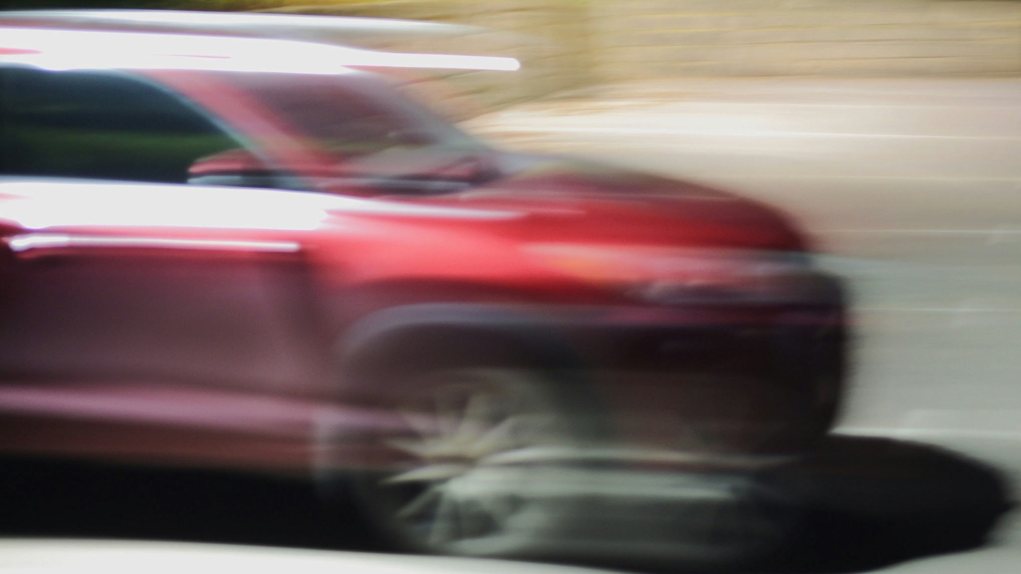 A blurry photo of a red car driving down a street