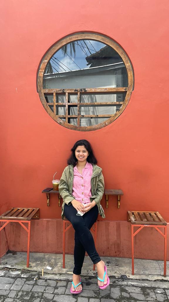 A thoughtful young person with dark hair gazes to the side, captured in soft black and white lighting.