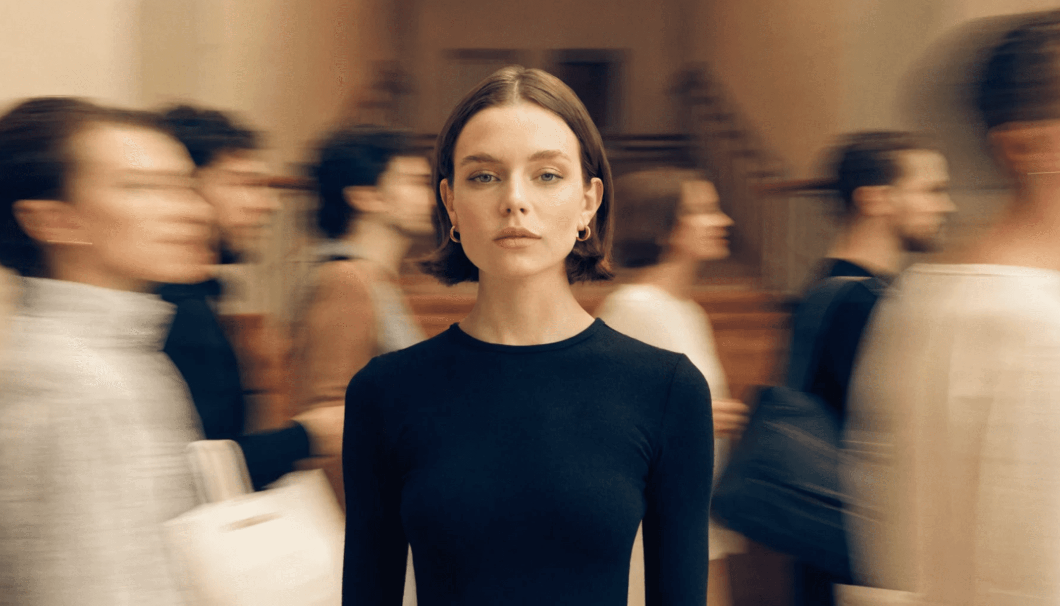 Woman in focus with blurred motion of people walking around her