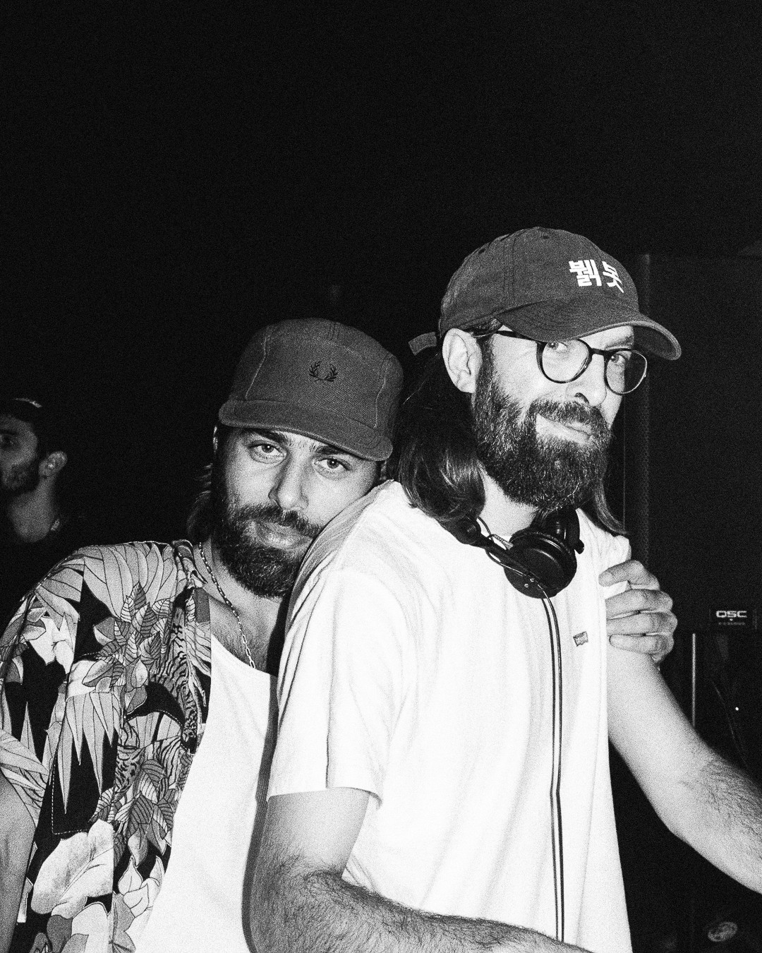 Duo Breakbot & Irfane posant ensemble, l'un portant une casquette et des lunettes, dans une atmosphère décontractée de studio ou de backstage.