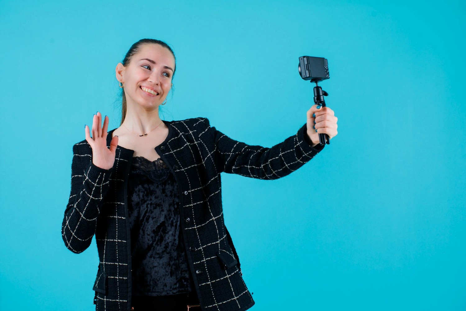  A woman using a selfie stick to capture a photo of herself in a vibrant outdoor setting.