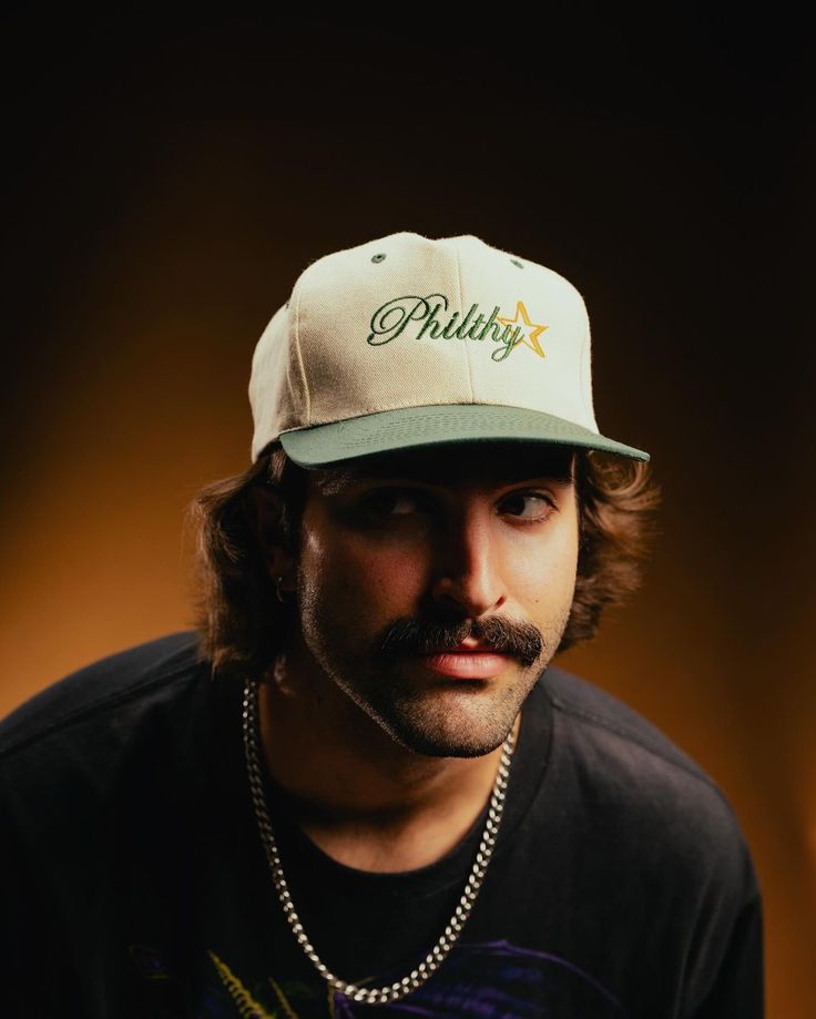 Side profile of a person wearing a red cap and yellow glasses against a red background.