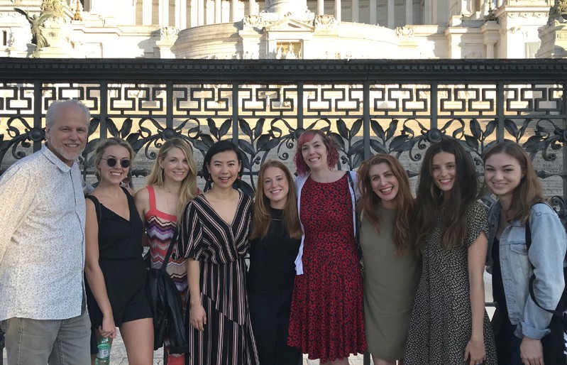 A photo of a group of people standing in front of some ancient building.