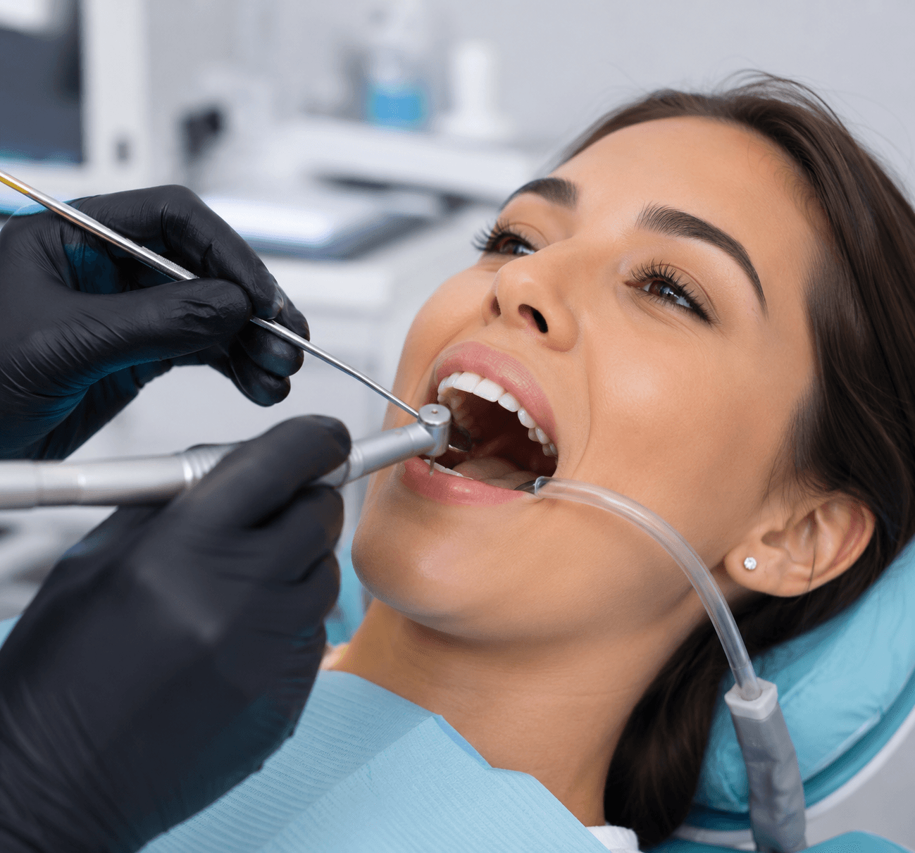 Dental professional in black gloves performing procedure with drill and mirror on patient in clinic
