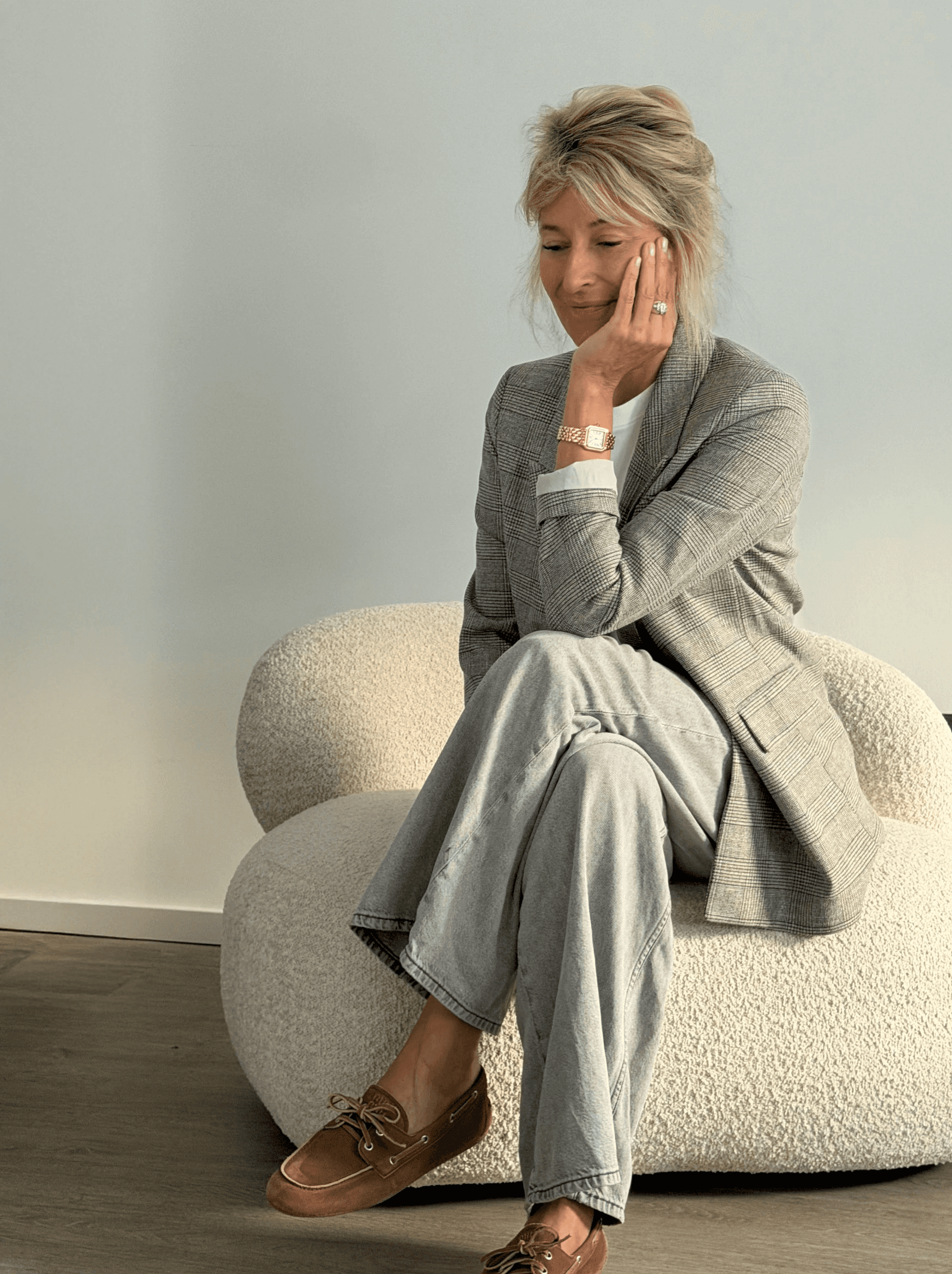 Woman in a light suit sitting thoughtfully against a terracotta wall