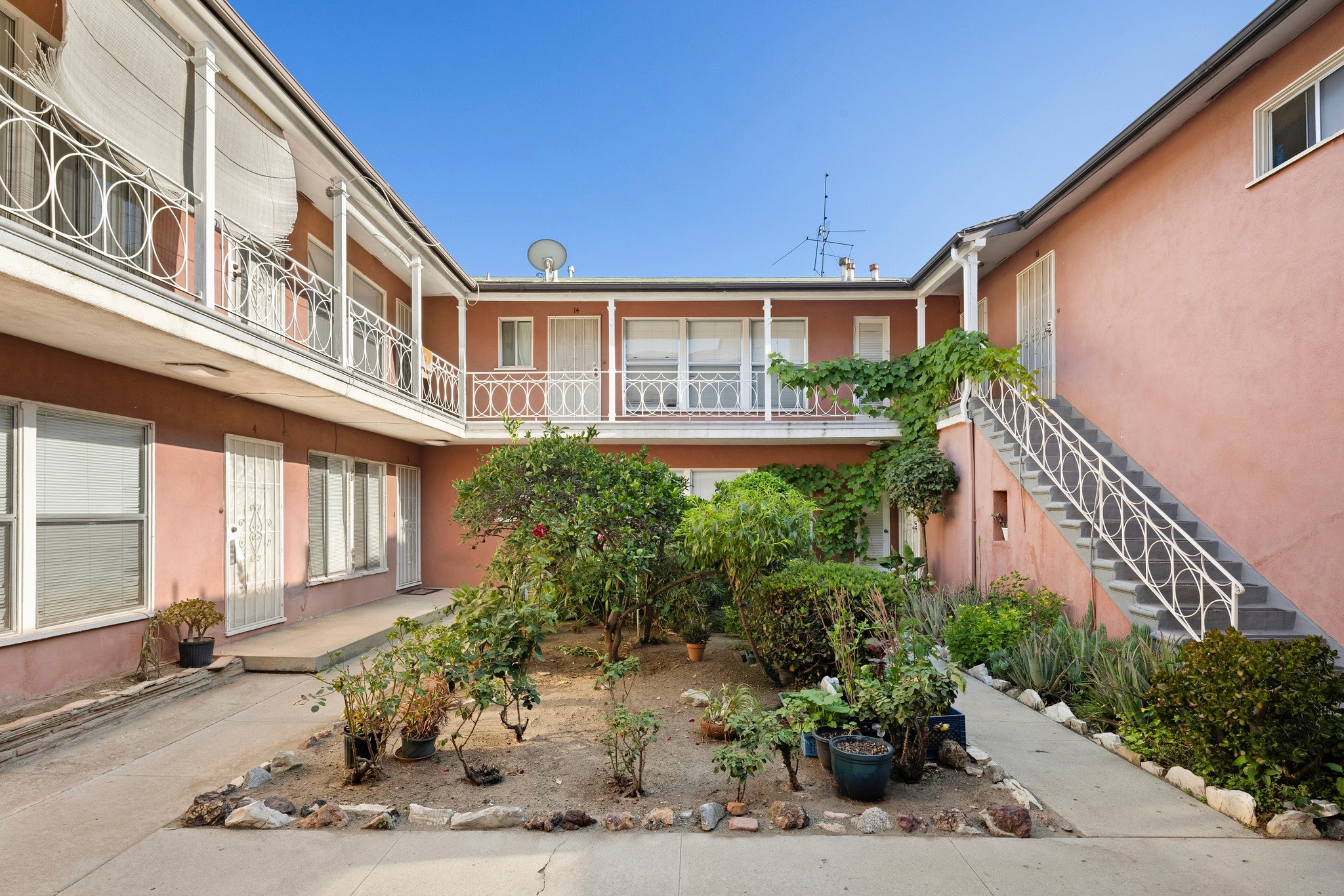 1640 N Harvard courtyard with landscaped garden, potted plants, and multi-unit residential building with balconies