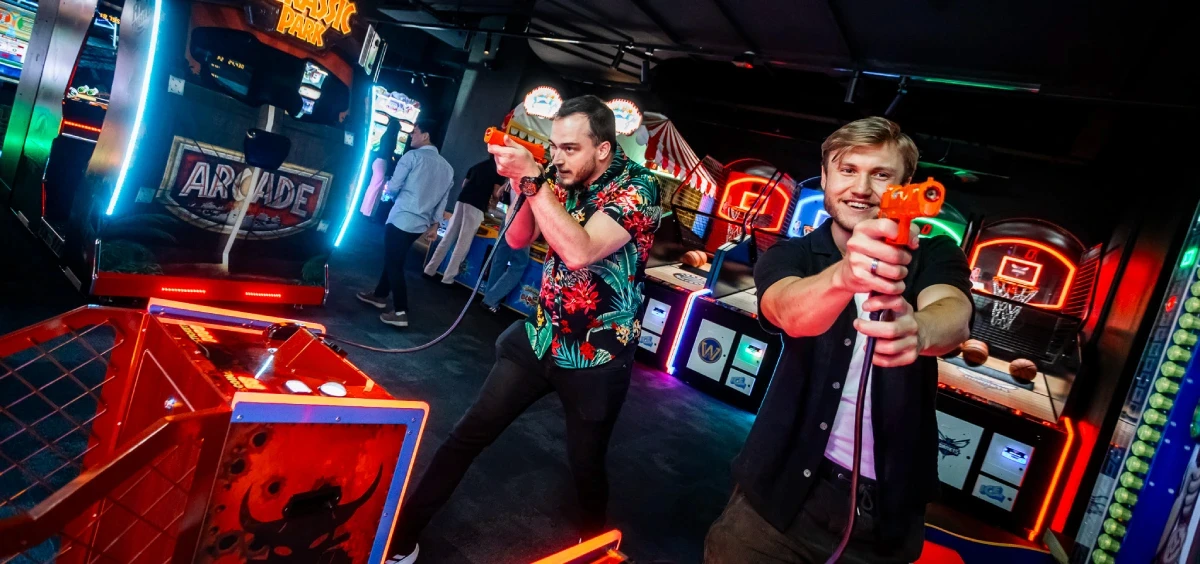 Three friends playing a light gun shooter arcade cabinet together