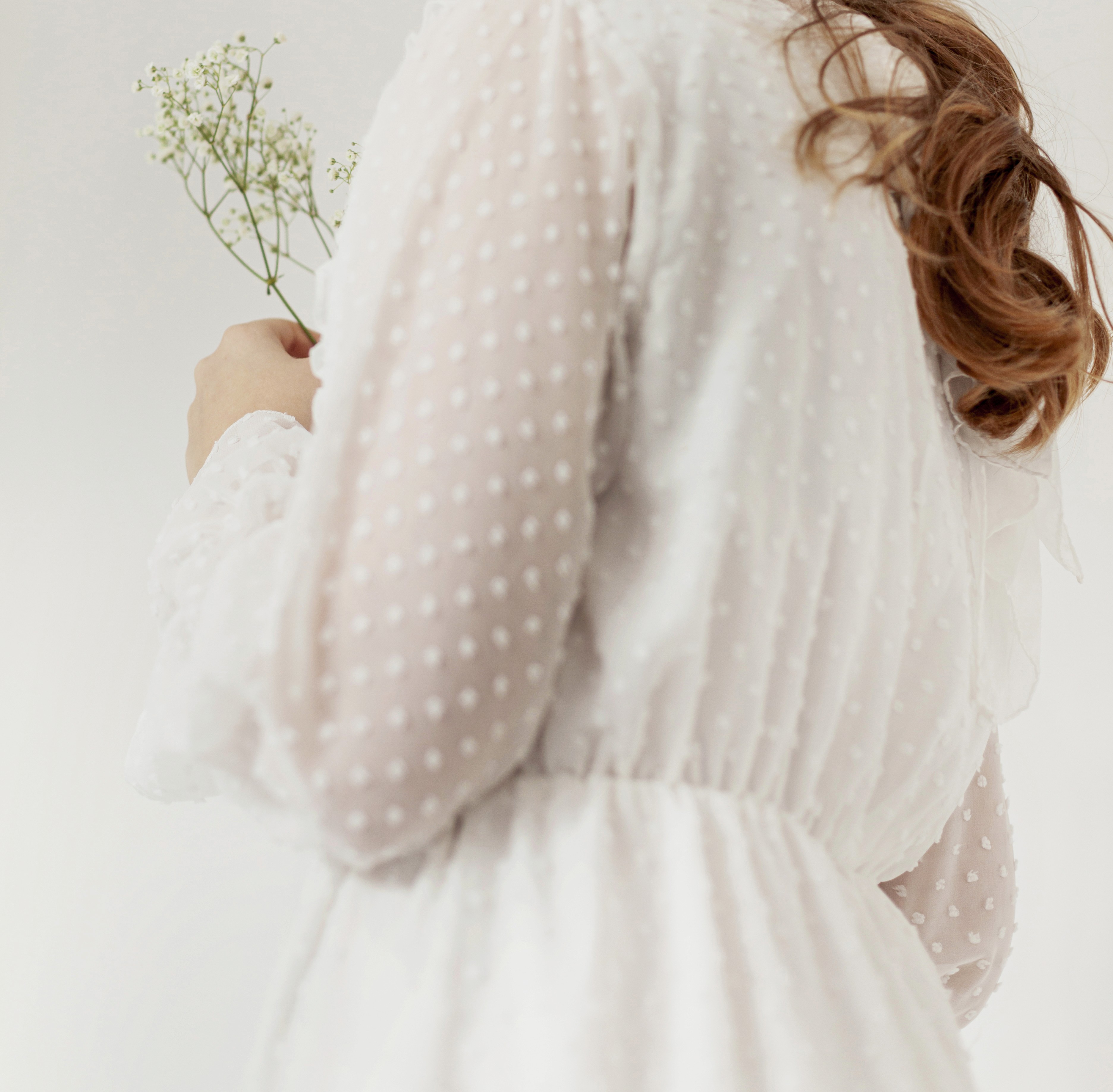 Vrouw die zich deels verschuilt achter een beige gordijn, symbool voor kwetsbaarheid en stilte rondom hormonale klachten