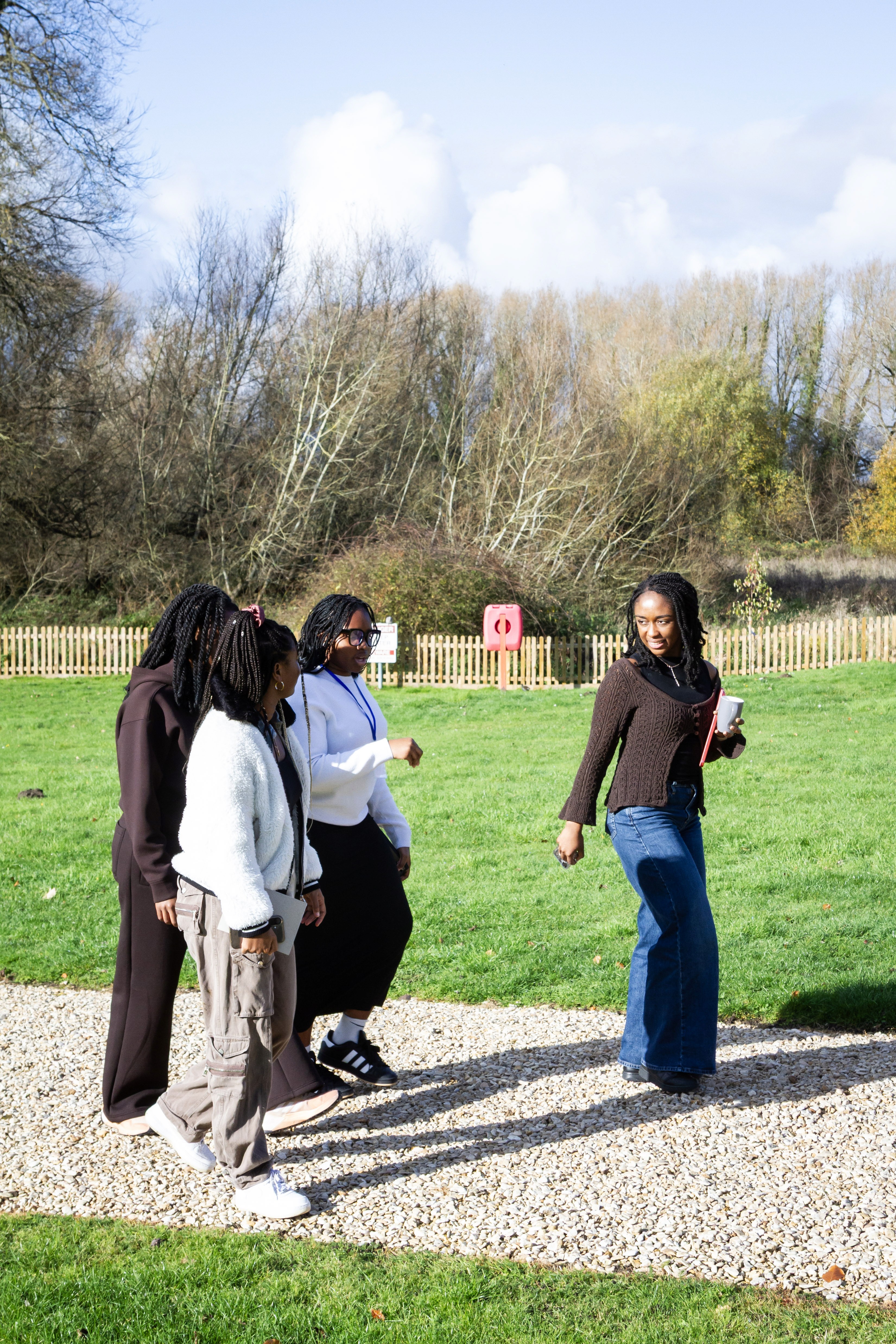 Four women walking together outdoors in the countryside and smiling.