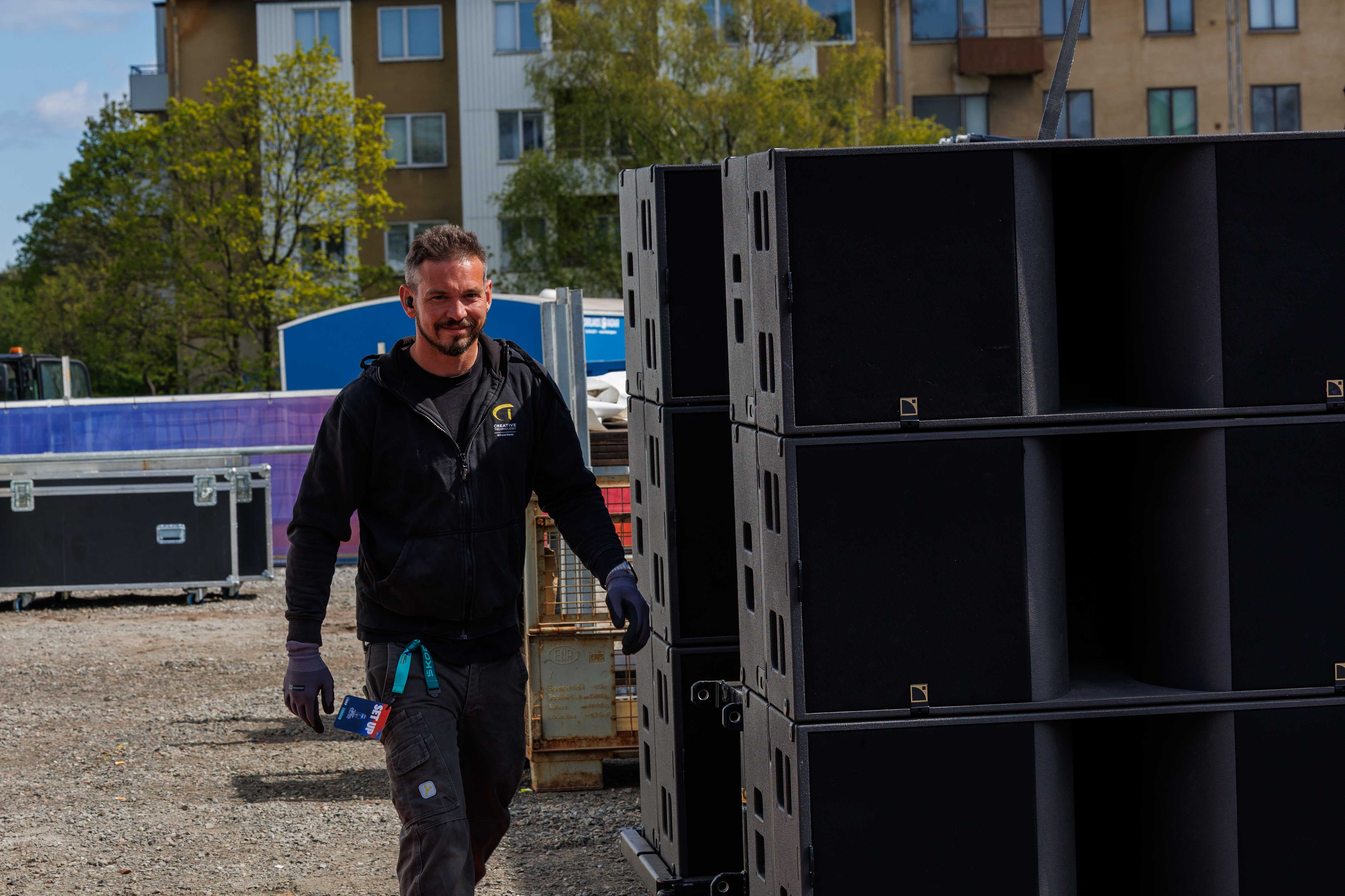 Portrait of a Creative Technology technician managing speaker setup during the load-in for the IIHF Ice Hockey World Championship 2025 fan zone.