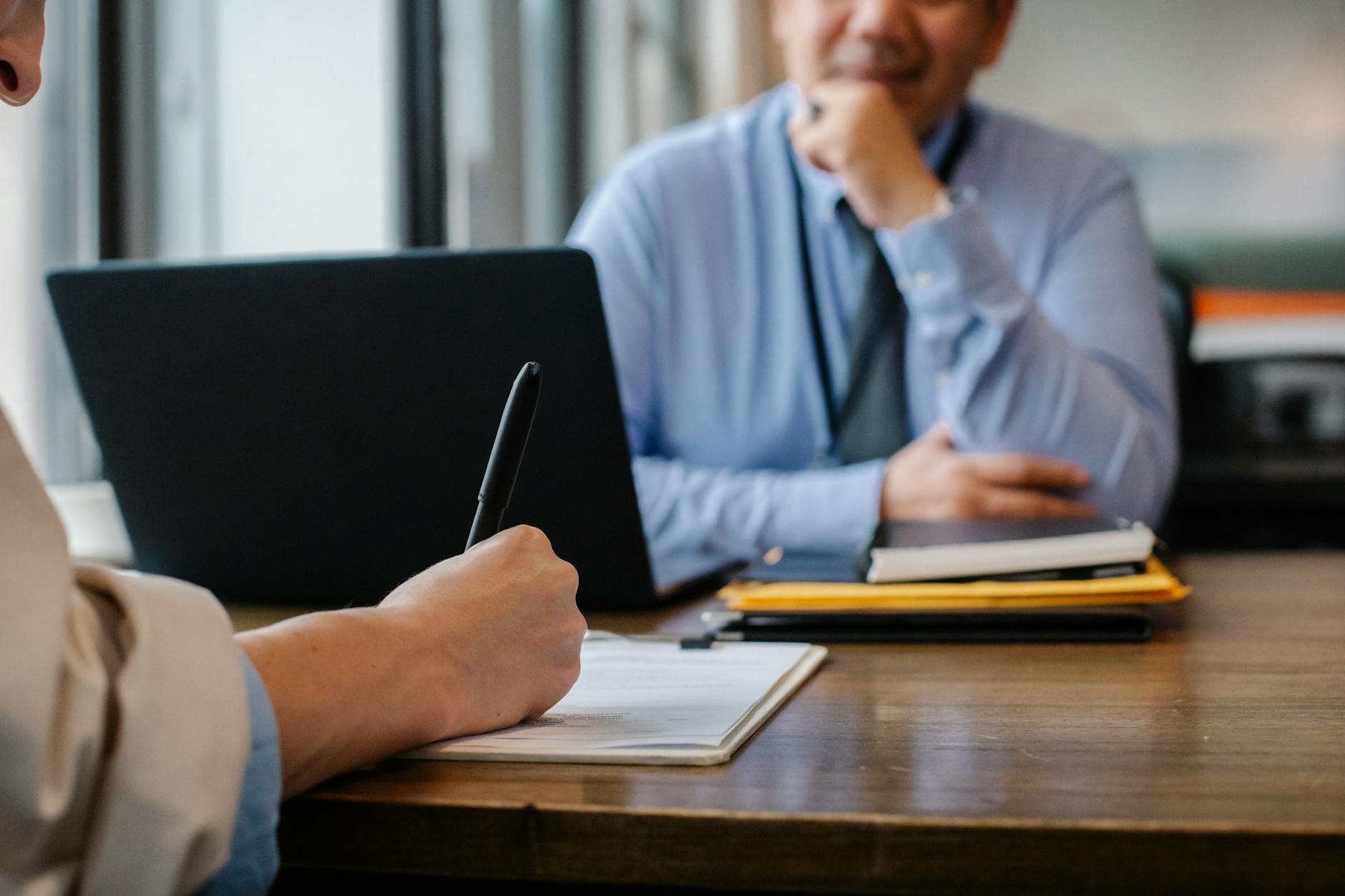 A professional leather portfolio and a printed resume sit on a clean desk next to a pair of glasses.
