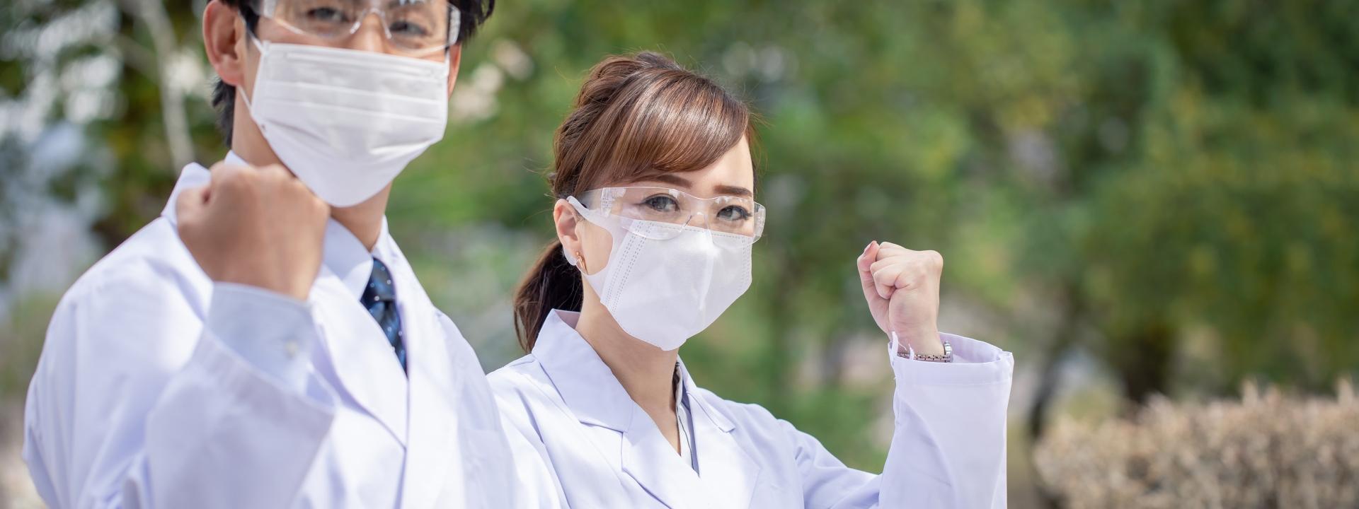 白衣とマスクで力強くガッツポーズする2人