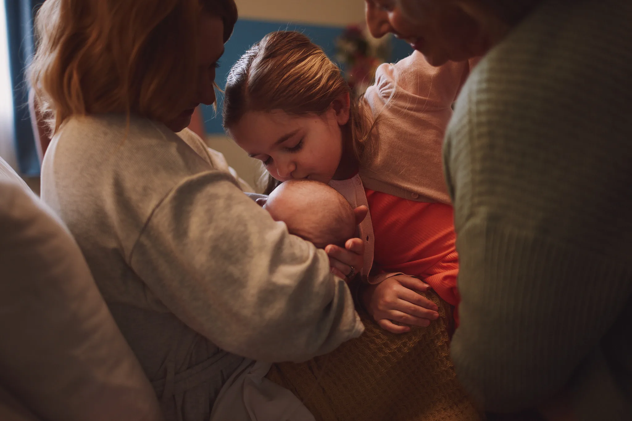 young girl kisses newborns head — lifestyle photography by Tom Kubik
