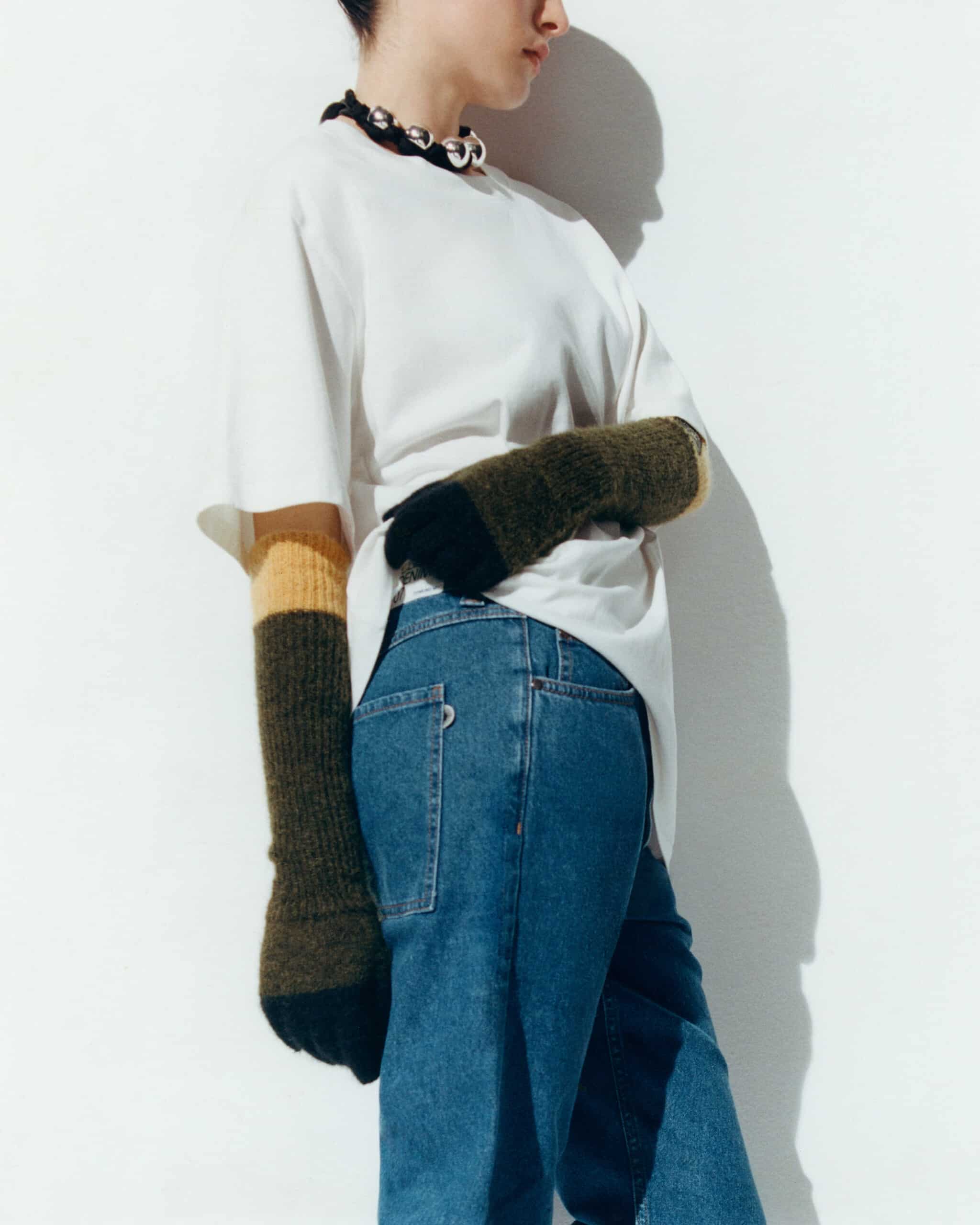Une mannequin Thinking Mu de côté porte t-shirt blanc et jean bleu