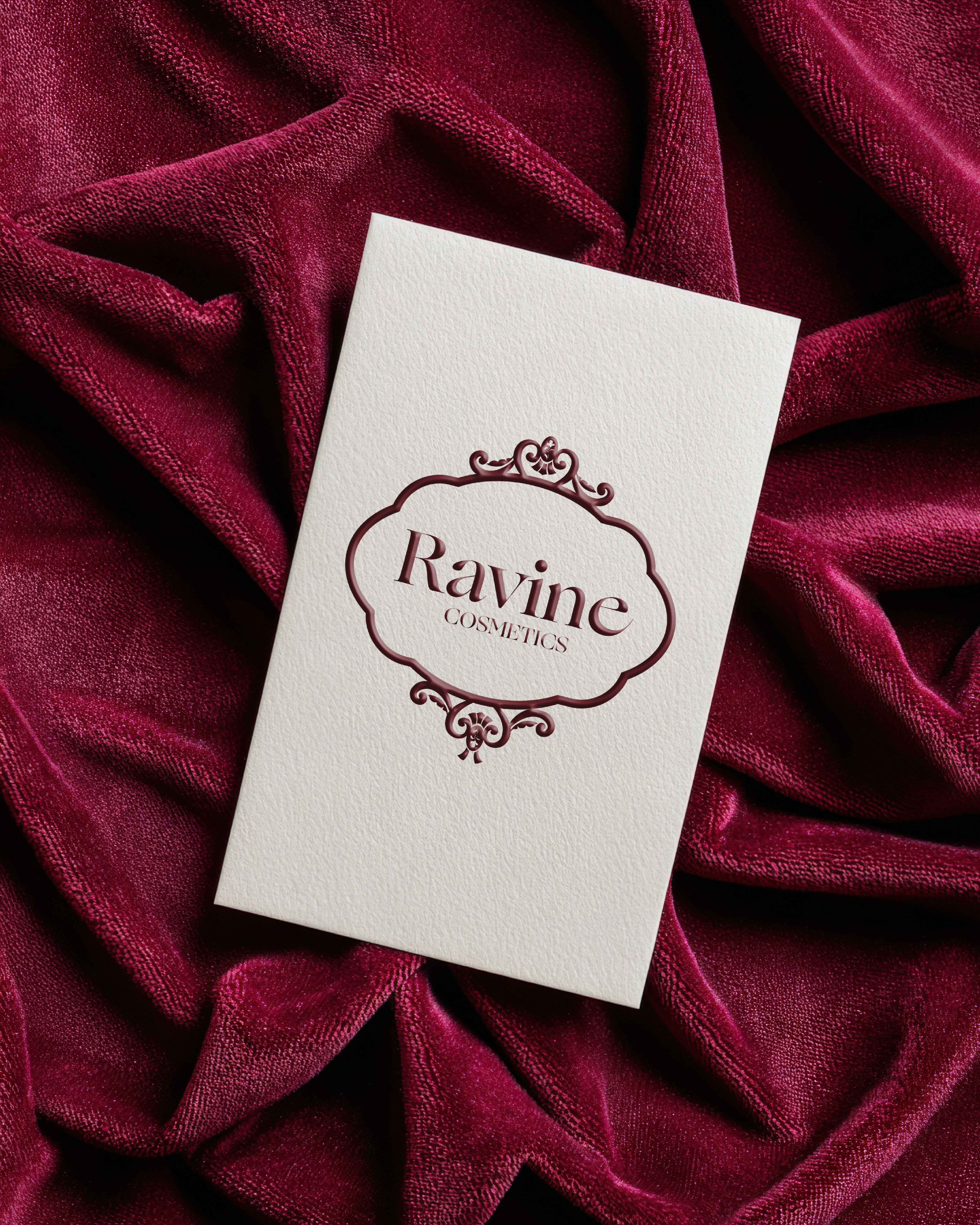 white business card featuring ravine logo that sits on top of a burgundy velvet surface