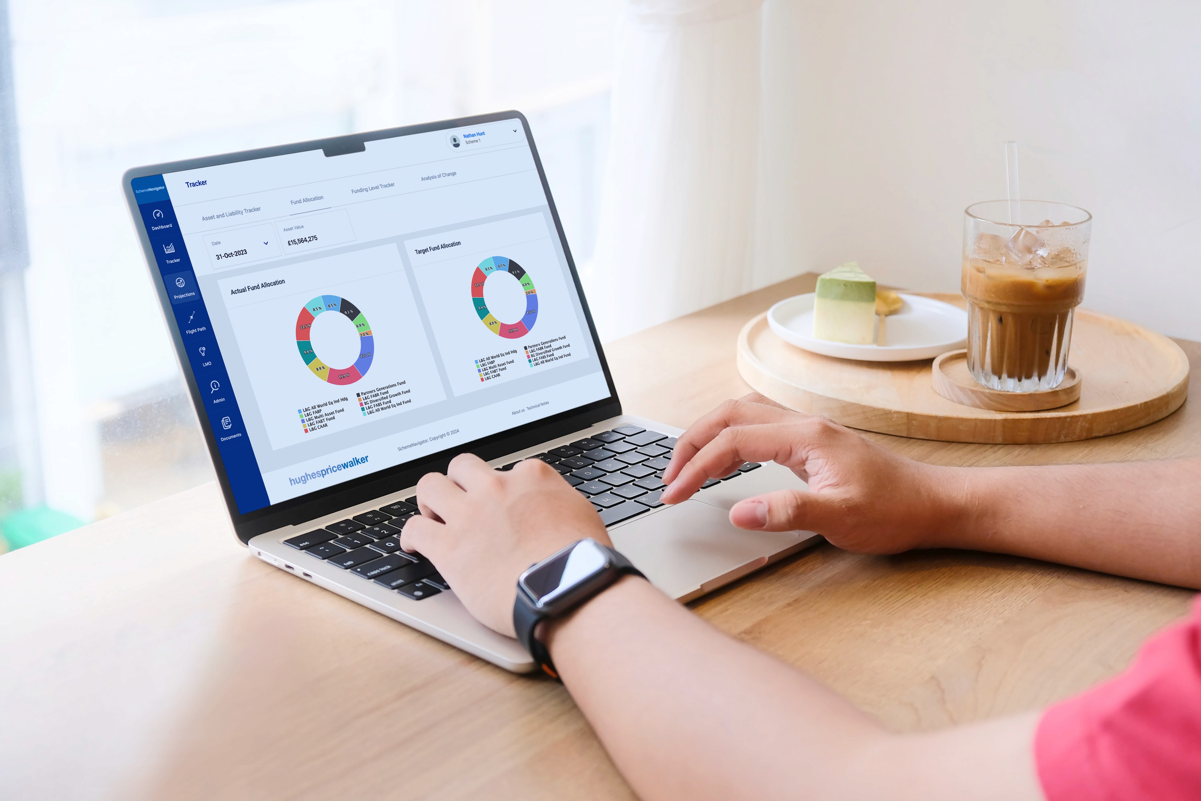Laptop showing the SchemeNavigator pension funding dashboard with asset and liability charts.