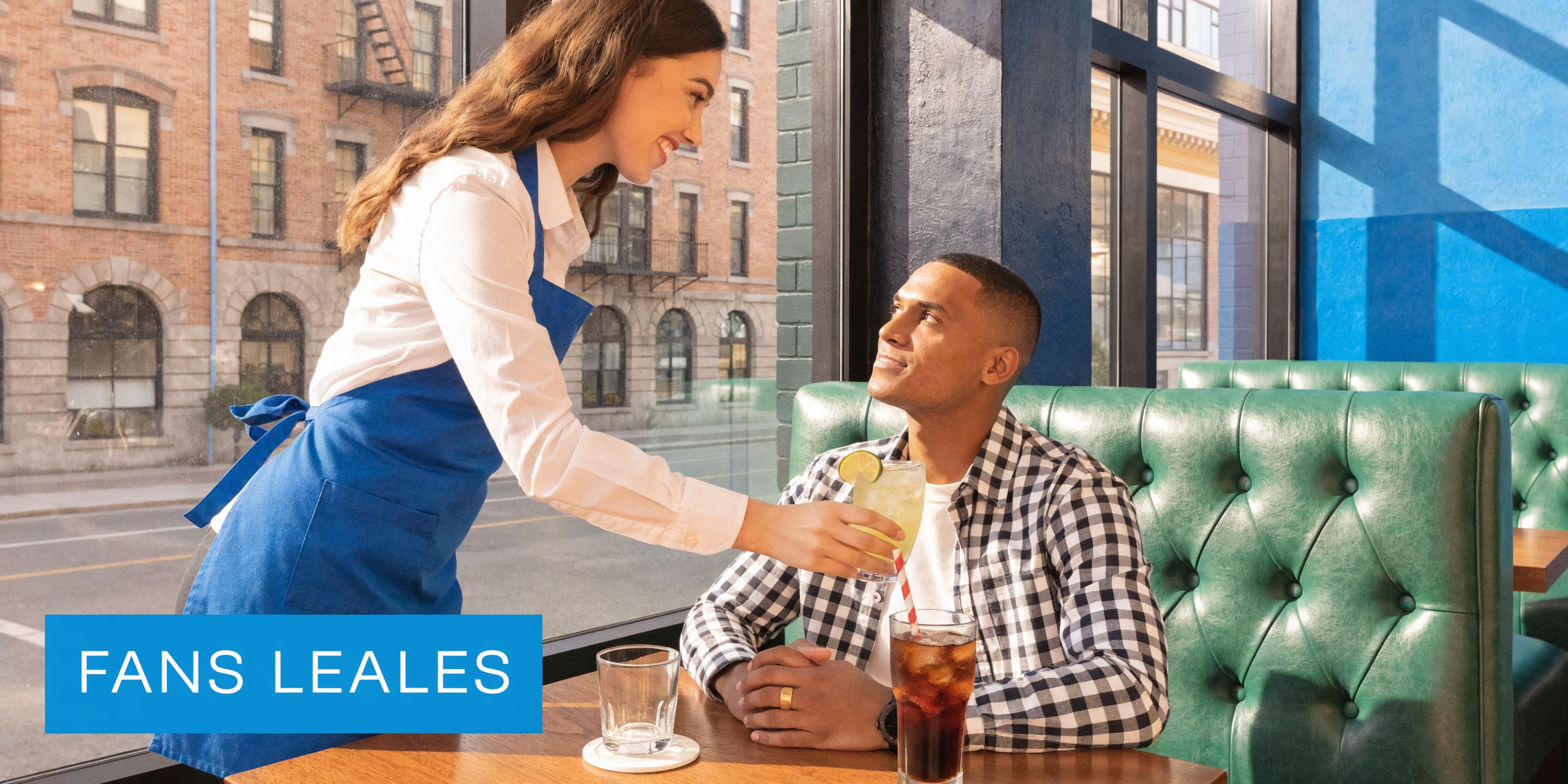 Una camarera amable sirve una bebida a un cliente sentado en un restaurante con cabinas verdes.