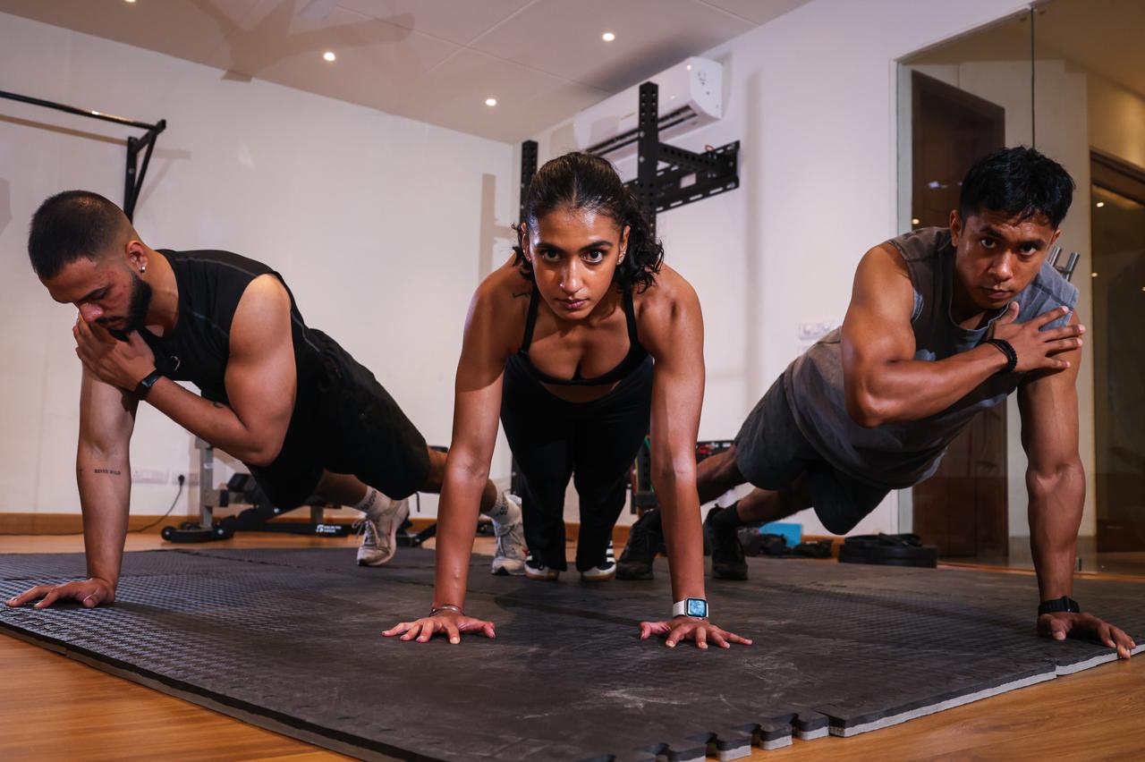 Two individuals are working out in a gym, focusing on dumbbells and strength training equipment.