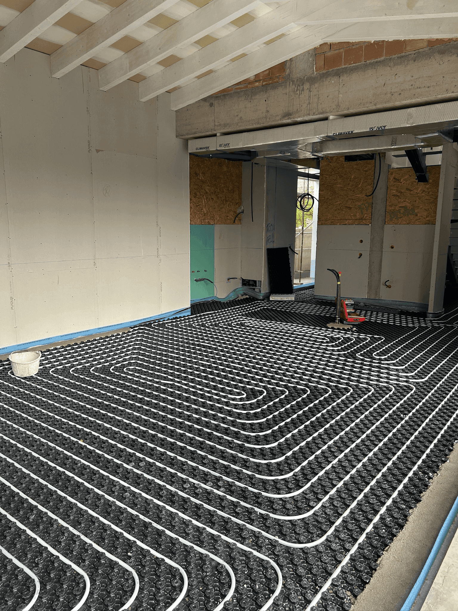 Instalación de suelo radiante por agua en una vivienda en construcción, con tuberías distribuidas sobre panel aislante antes del vertido del recrecido.