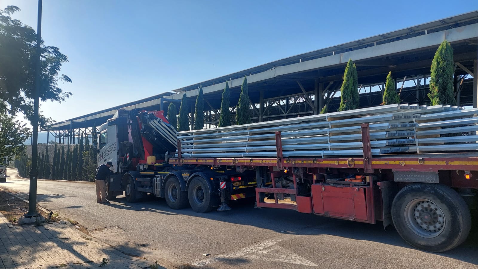 Modern glass and wood cabin with a cozy outdoor deck featuring wicker furniture, surrounded by lush green trees and a serene forest setting.