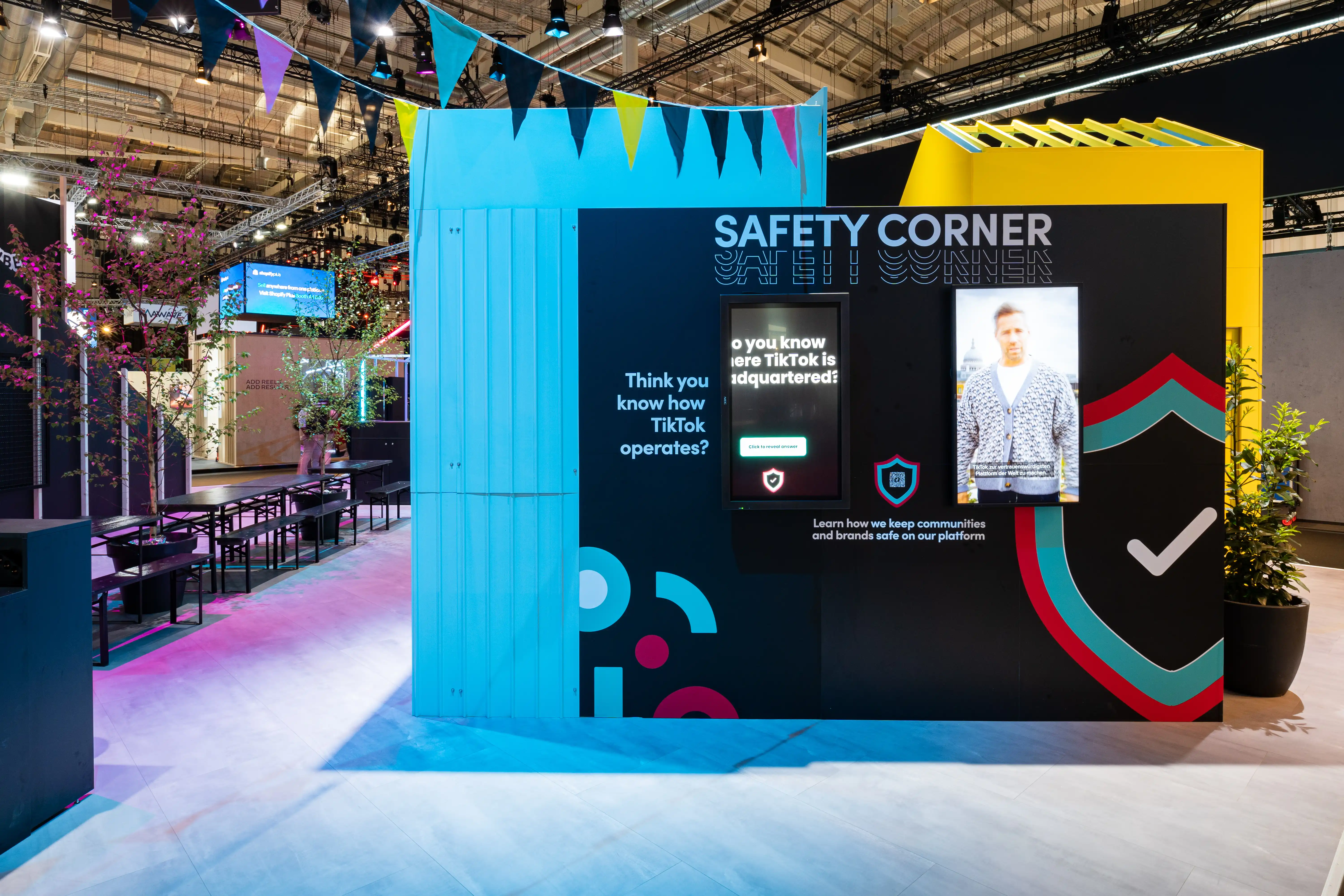Safety Corner of the TikTok booth with quiz screens, shield graphics and turquoise corrugated wall with bunting.