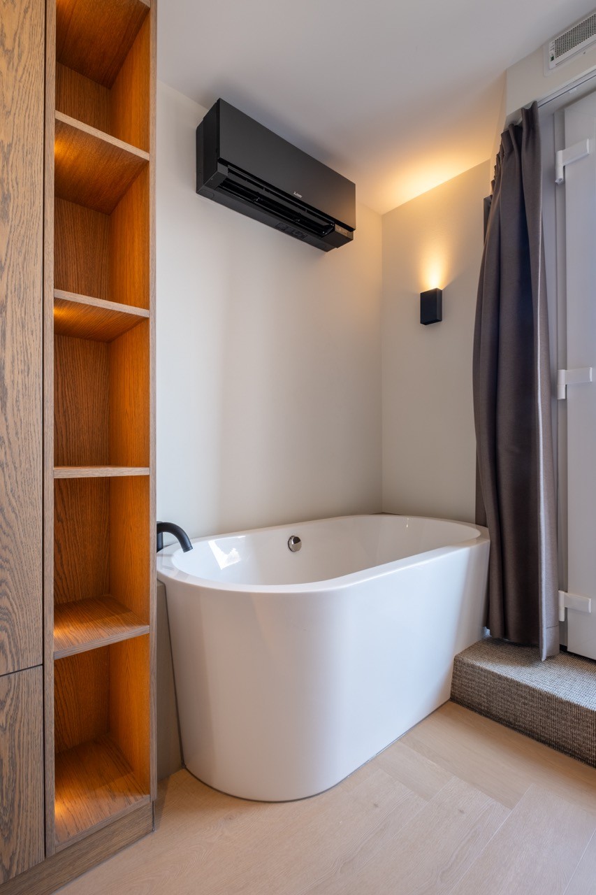 	Luxe badkamer met vrijstaand bad en houten details in suite nabij strand van Scheveningen