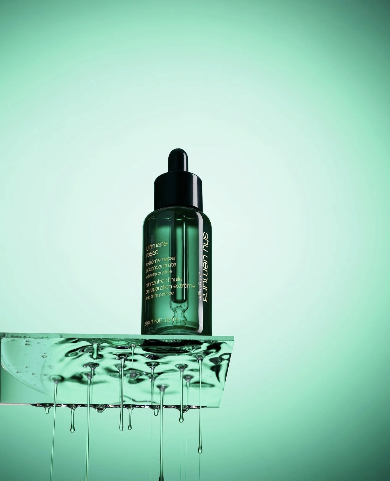 Smiling young woman with long hair standing against a dark green background, holding a finger to her chin.