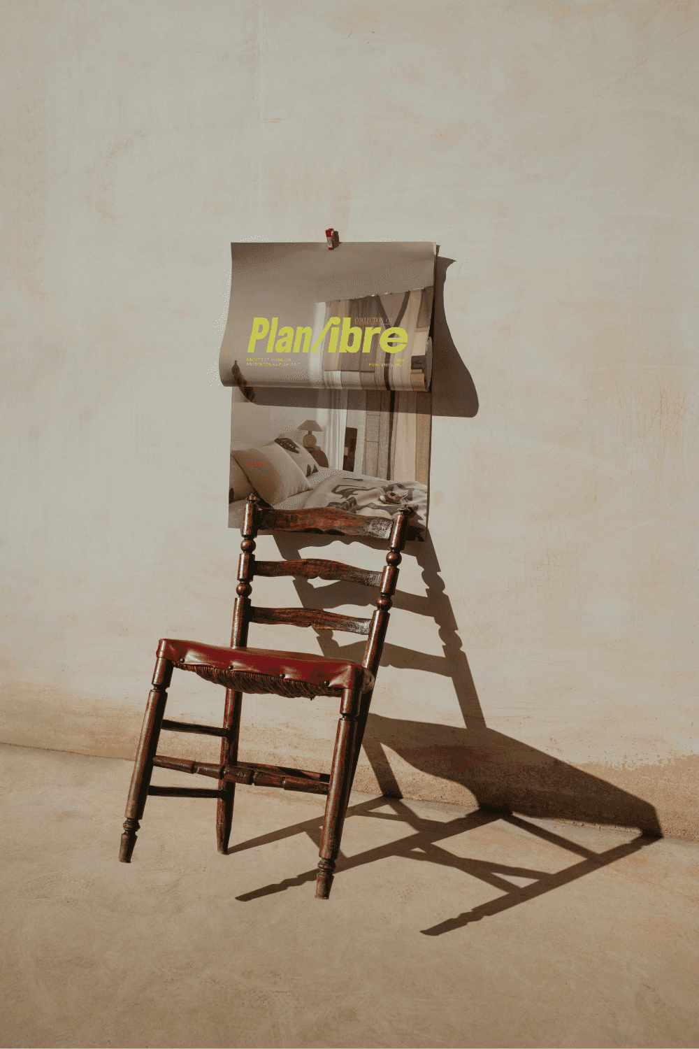Man in a white shirt reclines in a chair on a red carpet, talking on the phone. Scattered papers surround him, conveying stress or disarray.