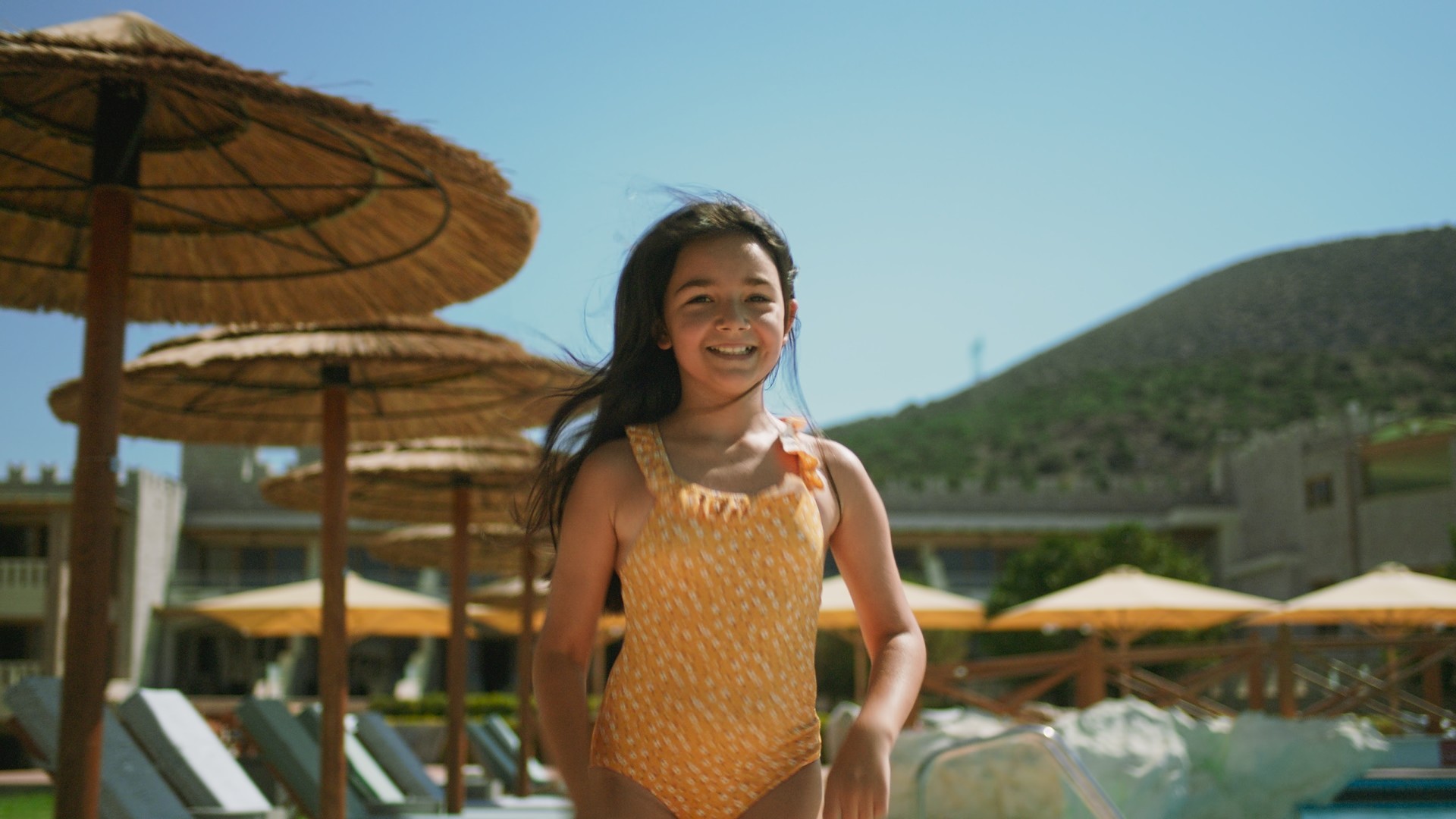 a child is running through the swimming pool with a yellow suit